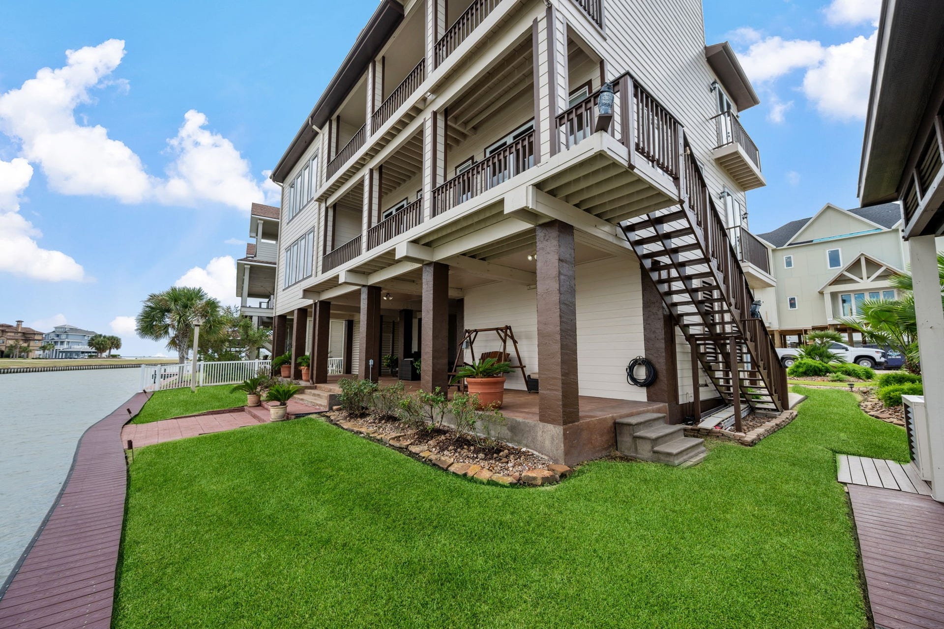 26 Half Moon, Hitchcock, TX 77563 Stunning waterfront home with multi-level balconies, lush landscaping, and direct access to a serene canal, perfect for outdoor living and relaxation.