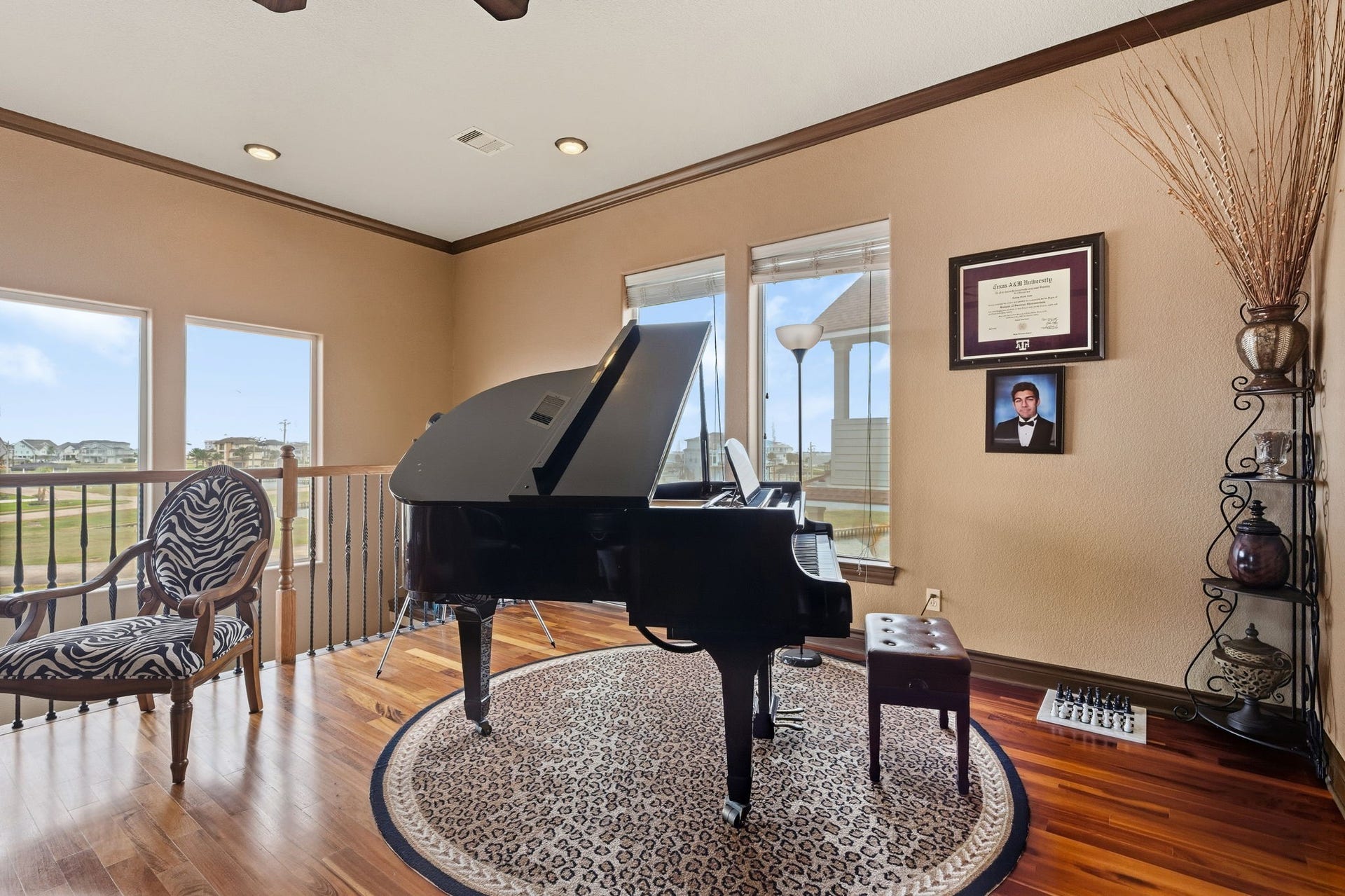 26 Half Moon, Hitchcock, TX 77563 Elegant music room featuring a grand piano, rich wood flooring, and ample natural light from large windows, creating a perfect ambiance for relaxation and creativity.