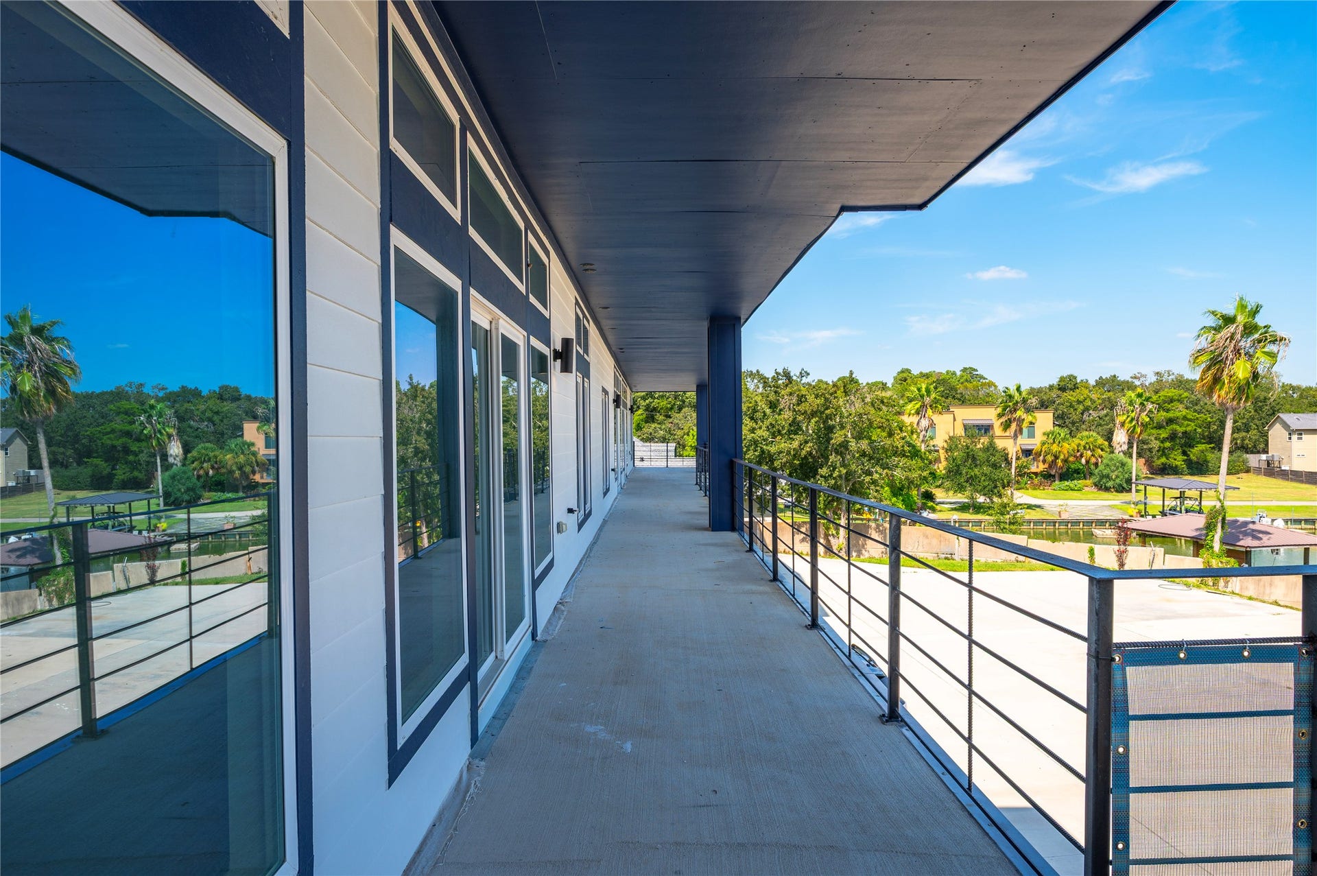 119 Kirby Road, #5201, Taylor Lake Village, TX 77586 Expansive balcony with sleek railings offers stunning views of lush greenery and palm trees, perfect for relaxation and outdoor enjoyment.