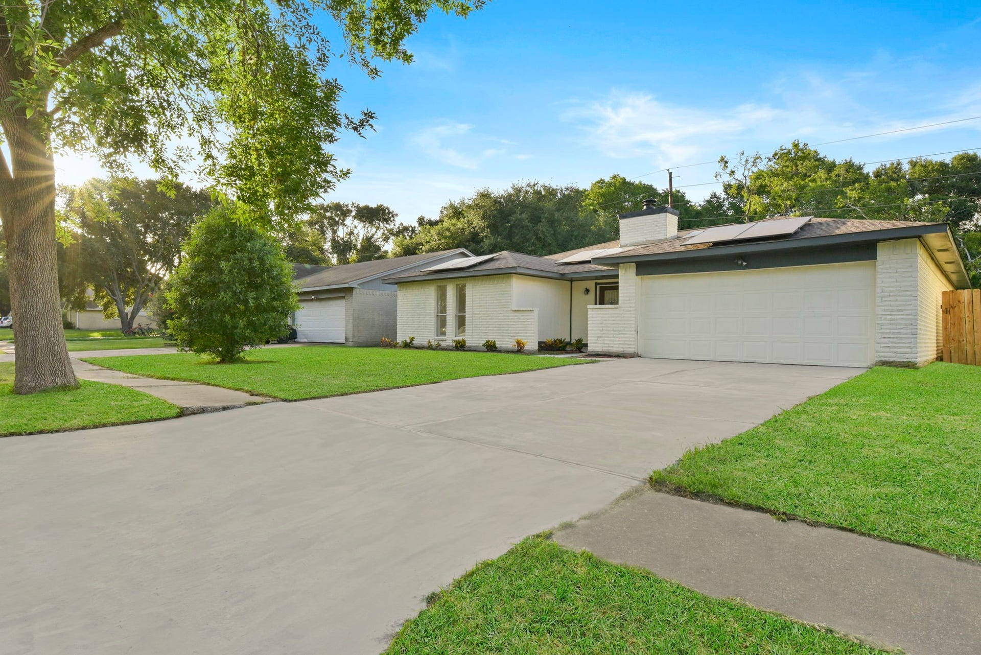 2322 Aprilmont Drive, Sugar Land, TX 77498 Charming single-story home with a spacious driveway and well-maintained lawn, featuring a modern exterior and solar panels for energy efficiency.