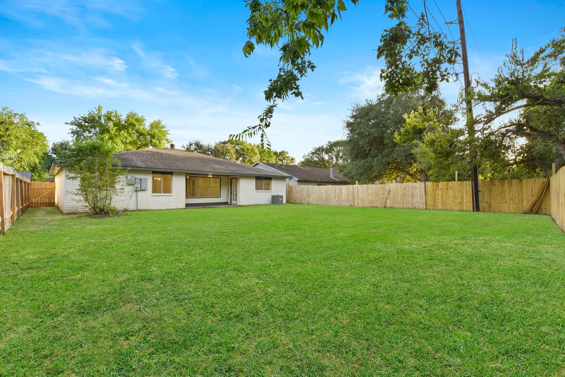 2322 Aprilmont Drive, Sugar Land, TX 77498 Expansive backyard with lush green lawn, perfect for outdoor activities and entertaining, complemented by a charming single-story home and privacy fencing.