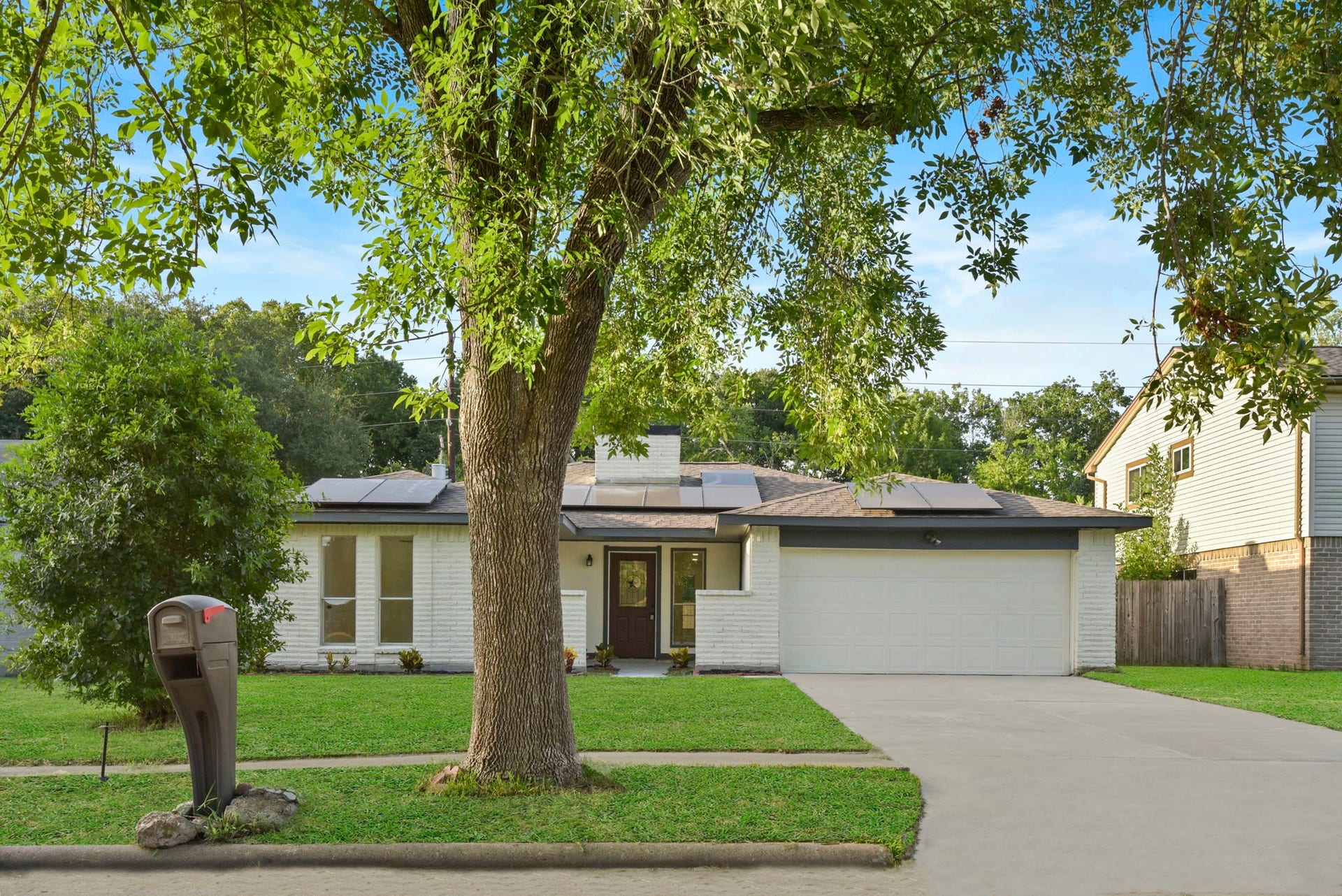 2322 Aprilmont Drive, Sugar Land, TX 77498 Charming single-story home with a modern vibe, featuring a spacious two-car garage and energy-efficient solar panels. Surrounded by lush greenery, the front yard offers a tranquil setting, enhanced by a mature tree and a well-maintained lawn.
