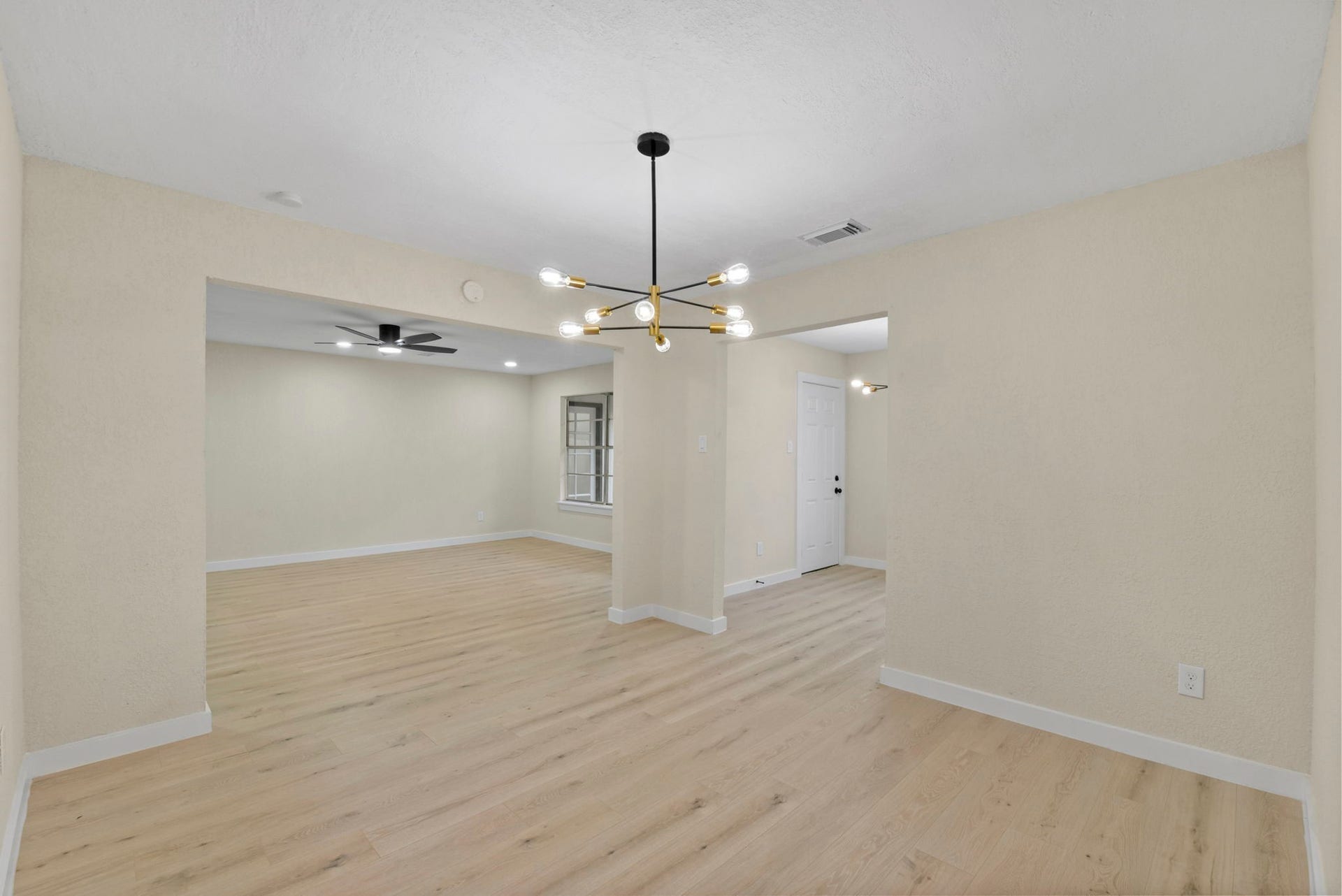 2322 Aprilmont Drive, Sugar Land, TX 77498 Bright and spacious living area with modern light fixtures, light wood flooring, and a neutral palette, offering a seamless flow between rooms.