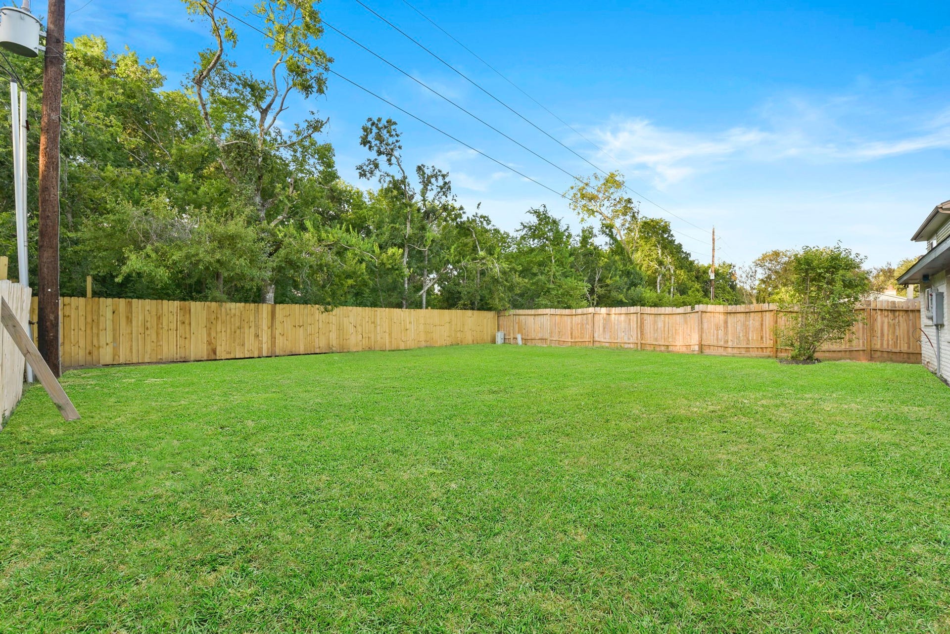 2322 Aprilmont Drive, Sugar Land, TX 77498 Spacious backyard with lush green lawn, surrounded by a wooden privacy fence, perfect for outdoor activities and relaxation.