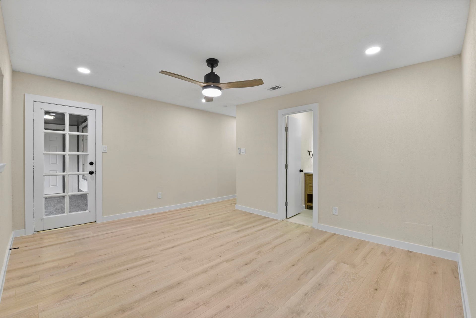 2322 Aprilmont Drive, Sugar Land, TX 77498 Bright and inviting room featuring sleek wood flooring, recessed lighting, and a modern ceiling fan, complemented by a door leading to an adjacent space.