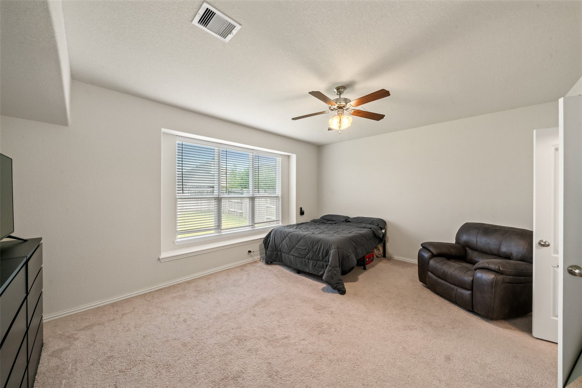 4509 Whitehaven Pine Way, Rosharon, TX 77583 Spacious bedroom with abundant natural light, featuring a large window, ceiling fan, and cozy carpet flooring.