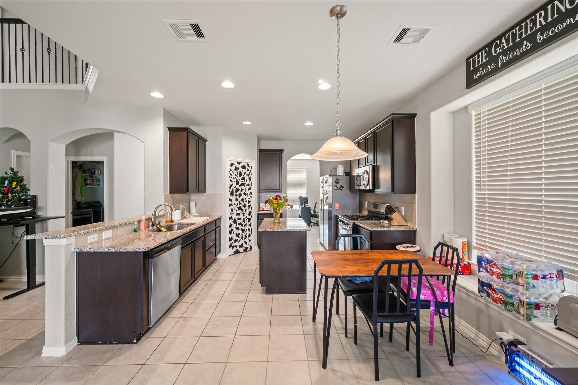 4509 Whitehaven Pine Way, Rosharon, TX 77583 Spacious kitchen with sleek dark cabinetry, stainless steel appliances, and a cozy breakfast nook, all under soft, natural lighting.