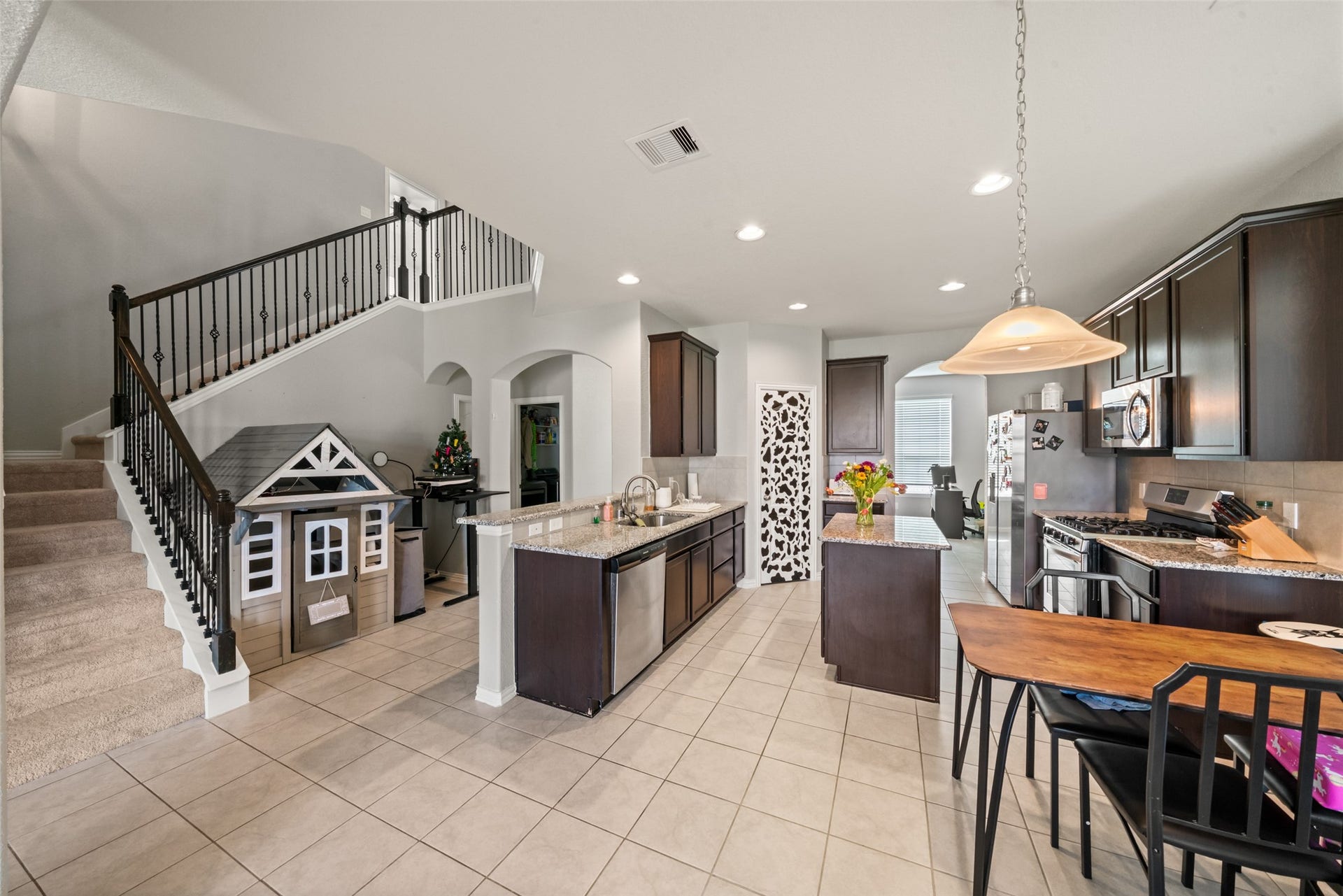4509 Whitehaven Pine Way, Rosharon, TX 77583 Spacious kitchen with sleek dark cabinetry, granite countertops, and modern appliances, complemented by an adjacent cozy dining area and stylish staircase.