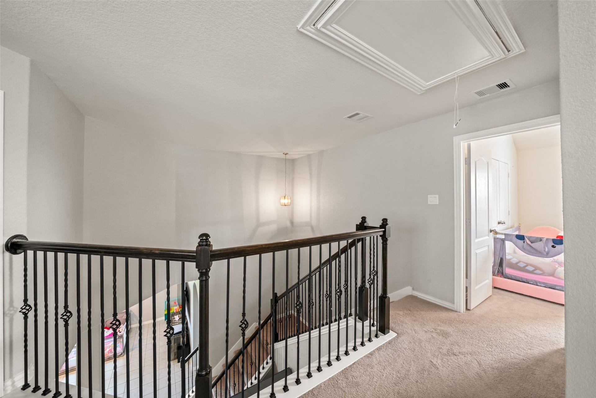 4509 Whitehaven Pine Way, Rosharon, TX 77583 Elegant upper landing with a stylish wrought iron railing, plush carpeting, and a cozy adjacent bedroom.