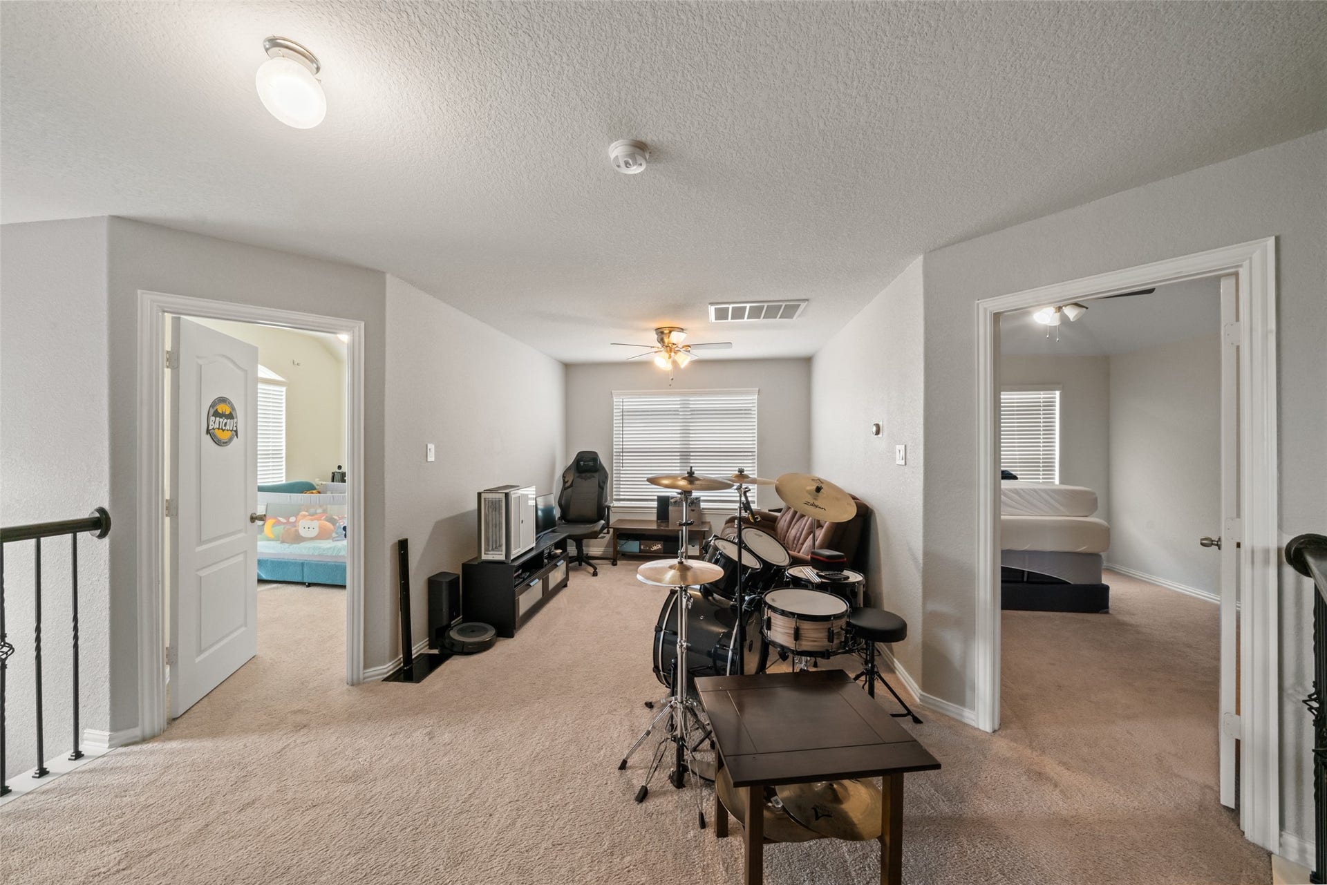 4509 Whitehaven Pine Way, Rosharon, TX 77583 Spacious upstairs bonus room with versatile potential, featuring a cozy carpeted area perfect for a music setup or gaming zone, flanked by two bedrooms with ample natural light.