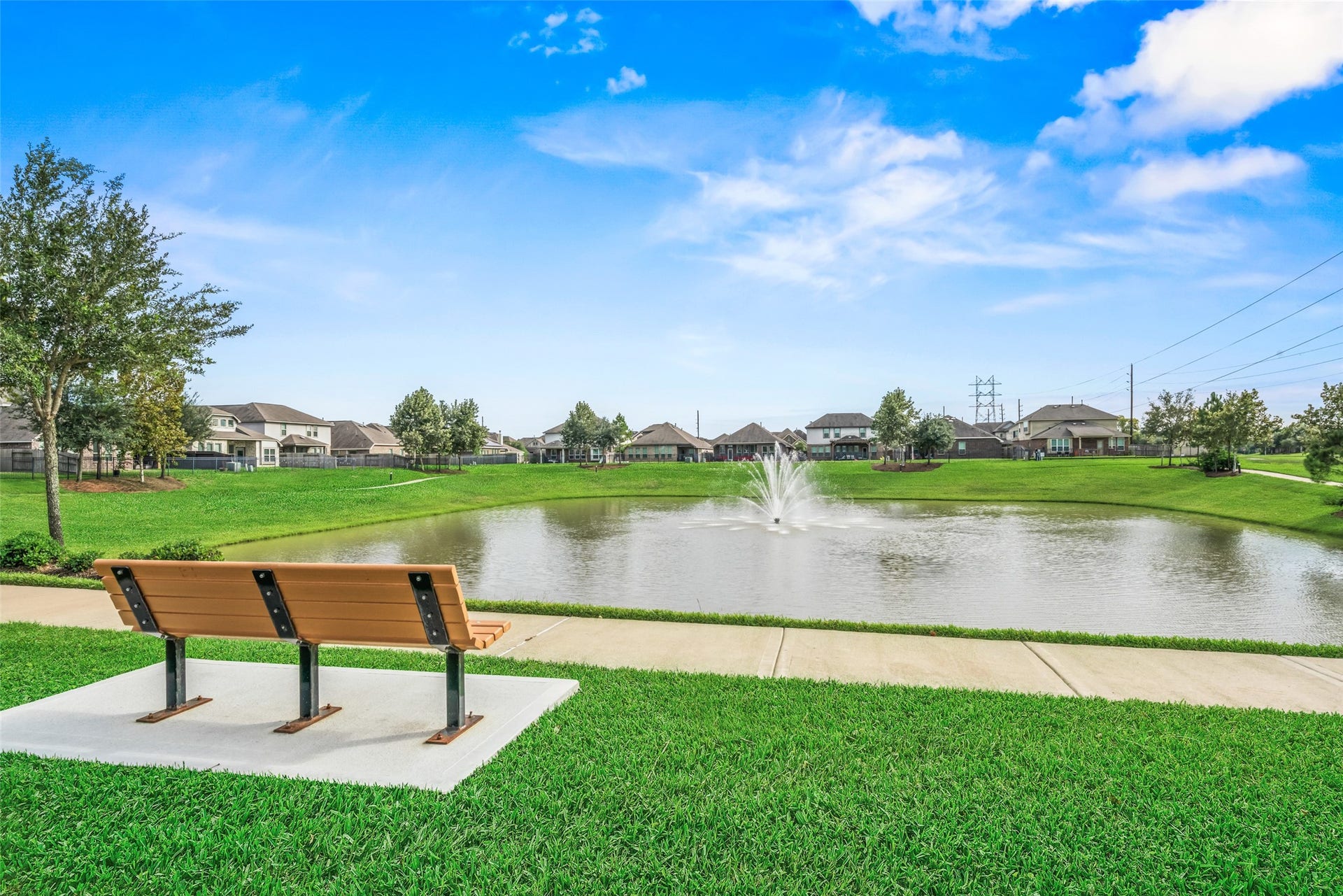 4509 Whitehaven Pine Way, Rosharon, TX 77583 Enjoy serene views of the community pond with a charming fountain, perfect for relaxation on the nearby bench amidst lush greenery.