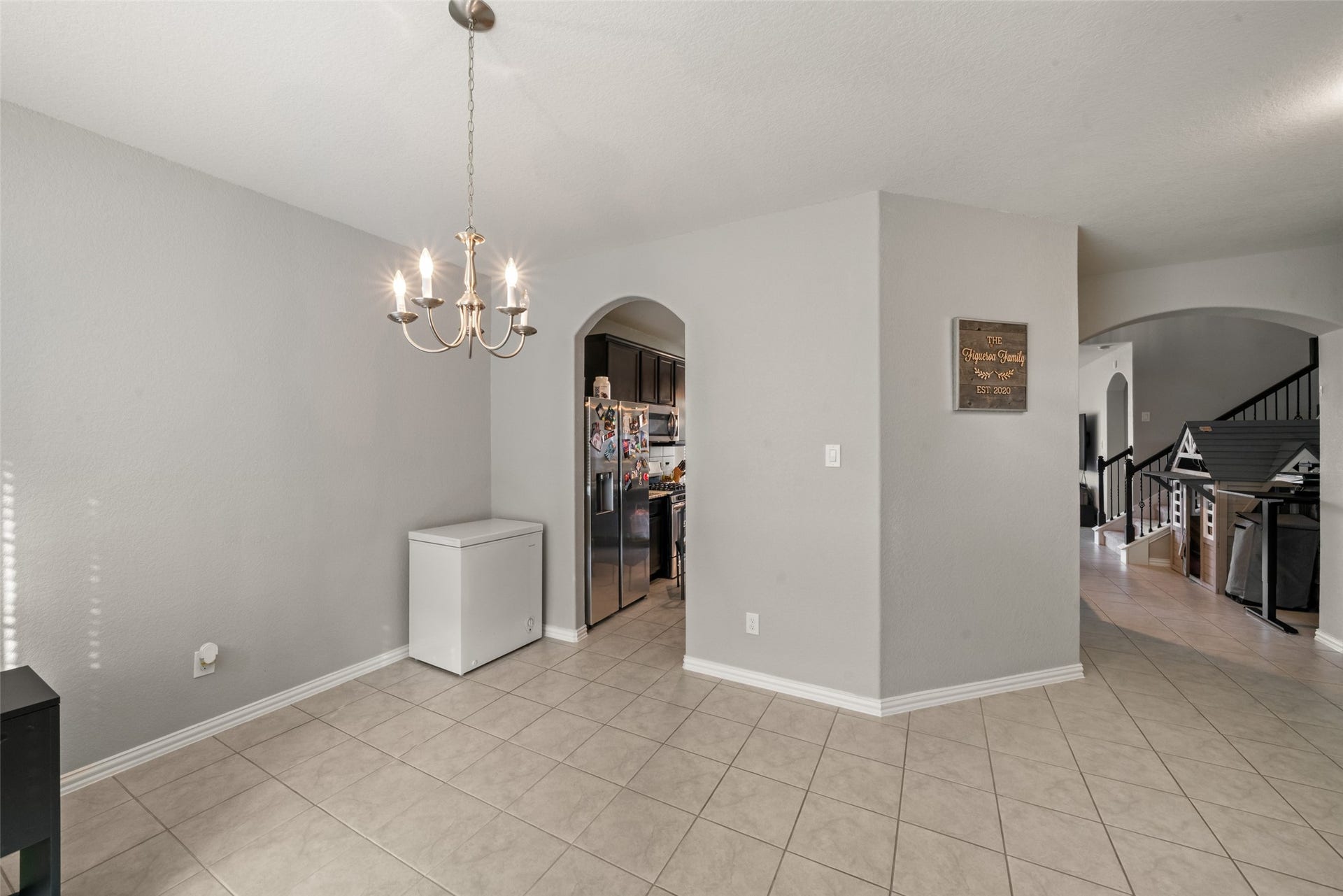 4509 Whitehaven Pine Way, Rosharon, TX 77583 Bright and open dining area with elegant tile flooring, a charming chandelier, and convenient access to the kitchen and living spaces through stylish archways.
