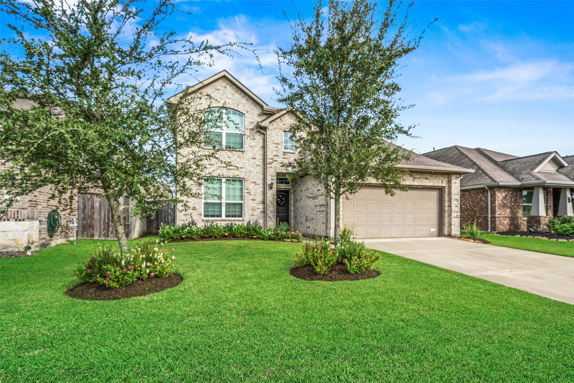 4509 Whitehaven Pine Way, Rosharon, TX 77583 Appealing two-story brick home with a well-maintained lawn and vibrant landscaping, featuring a spacious driveway leading to an attached two-car garage.