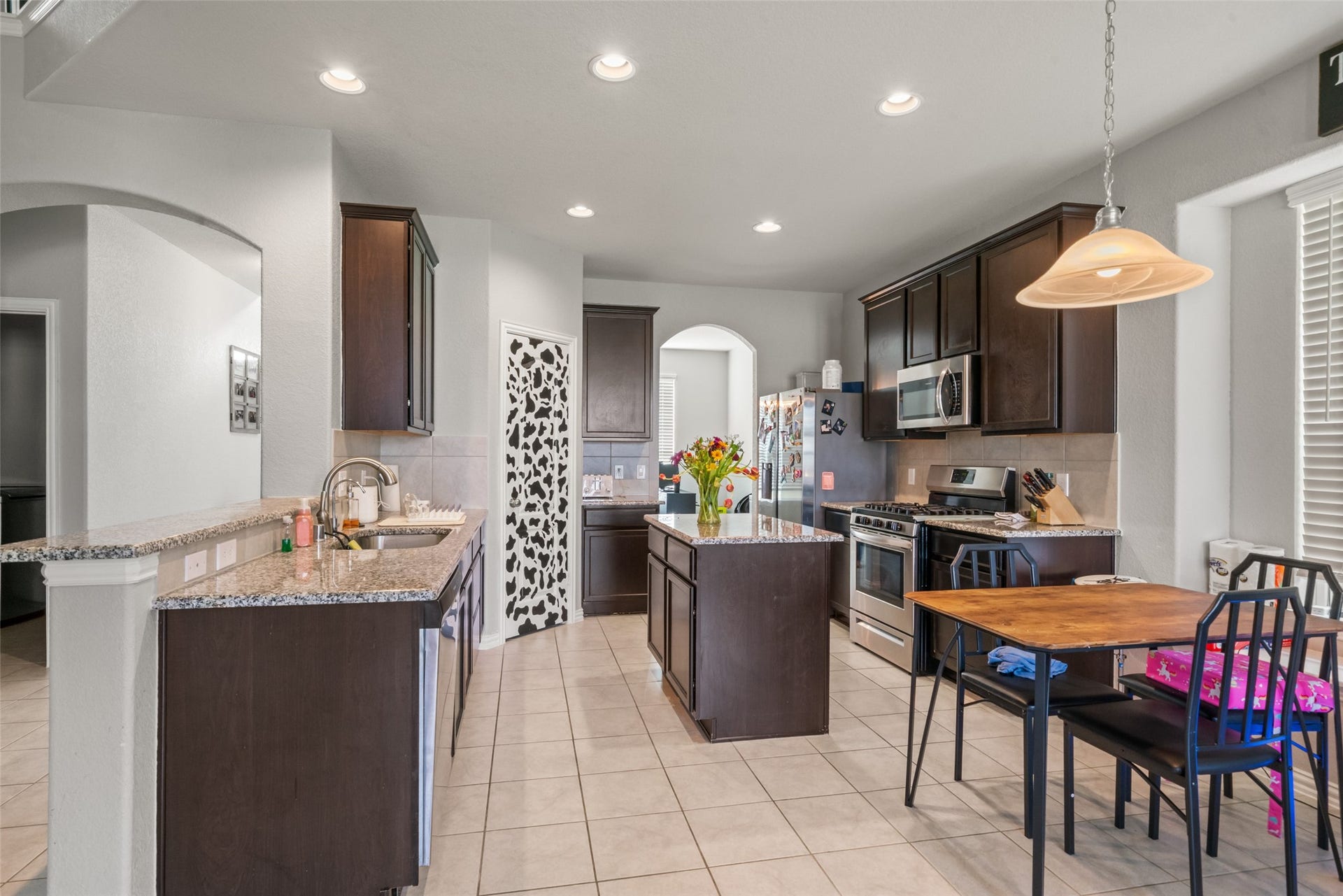 4509 Whitehaven Pine Way, Rosharon, TX 77583 Bright and modern kitchen with dark wood cabinetry, granite countertops, and stainless steel appliances. Features a central island, cozy dining area, and ample lighting.