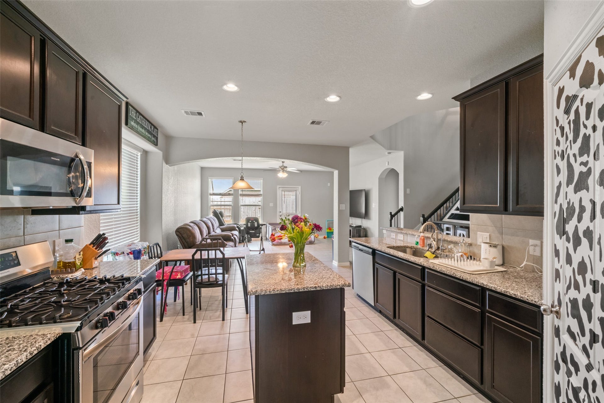 4509 Whitehaven Pine Way, Rosharon, TX 77583 Spacious open-concept kitchen with dark cabinetry, granite countertops, and a central island, seamlessly flowing into a cozy living area with ample natural light.