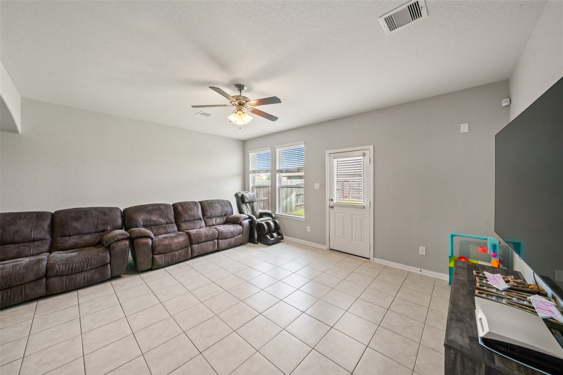 4509 Whitehaven Pine Way, Rosharon, TX 77583 Spacious living area with tiled floors, ample natural light from large windows, and a area large enough to enjoy the game, perfect for relaxation and entertainment.