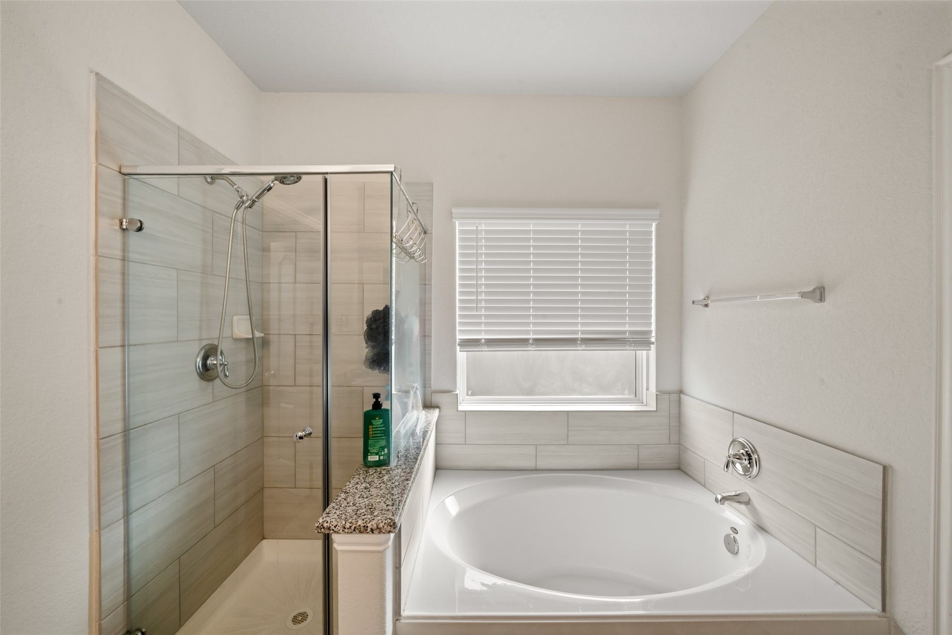 4509 Whitehaven Pine Way, Rosharon, TX 77583 Primary bathroom featuring a sleek glass-enclosed shower and a spacious bathtub, complemented by elegant tile work and natural light from a large window.