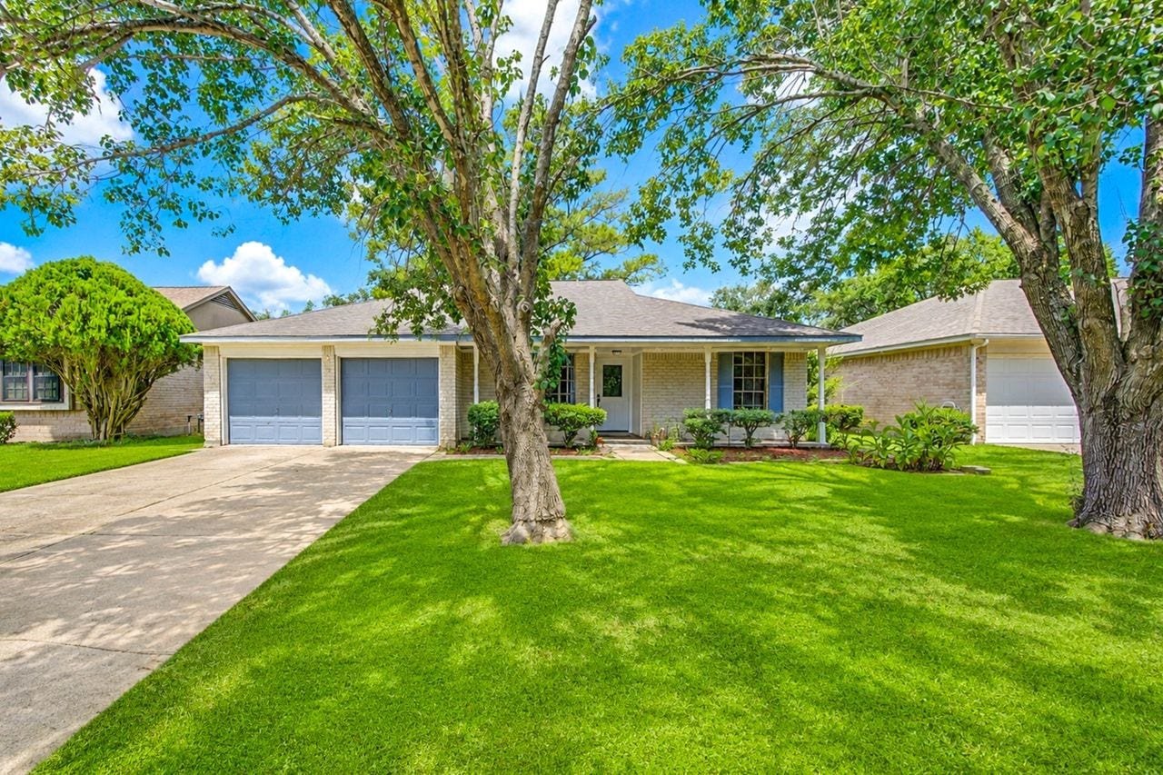15107 Mcconn Street, Houston, TX 77598 Charming single-story home with a two-car garage, nestled among mature trees and lush landscaping, offering excellent curb appeal.