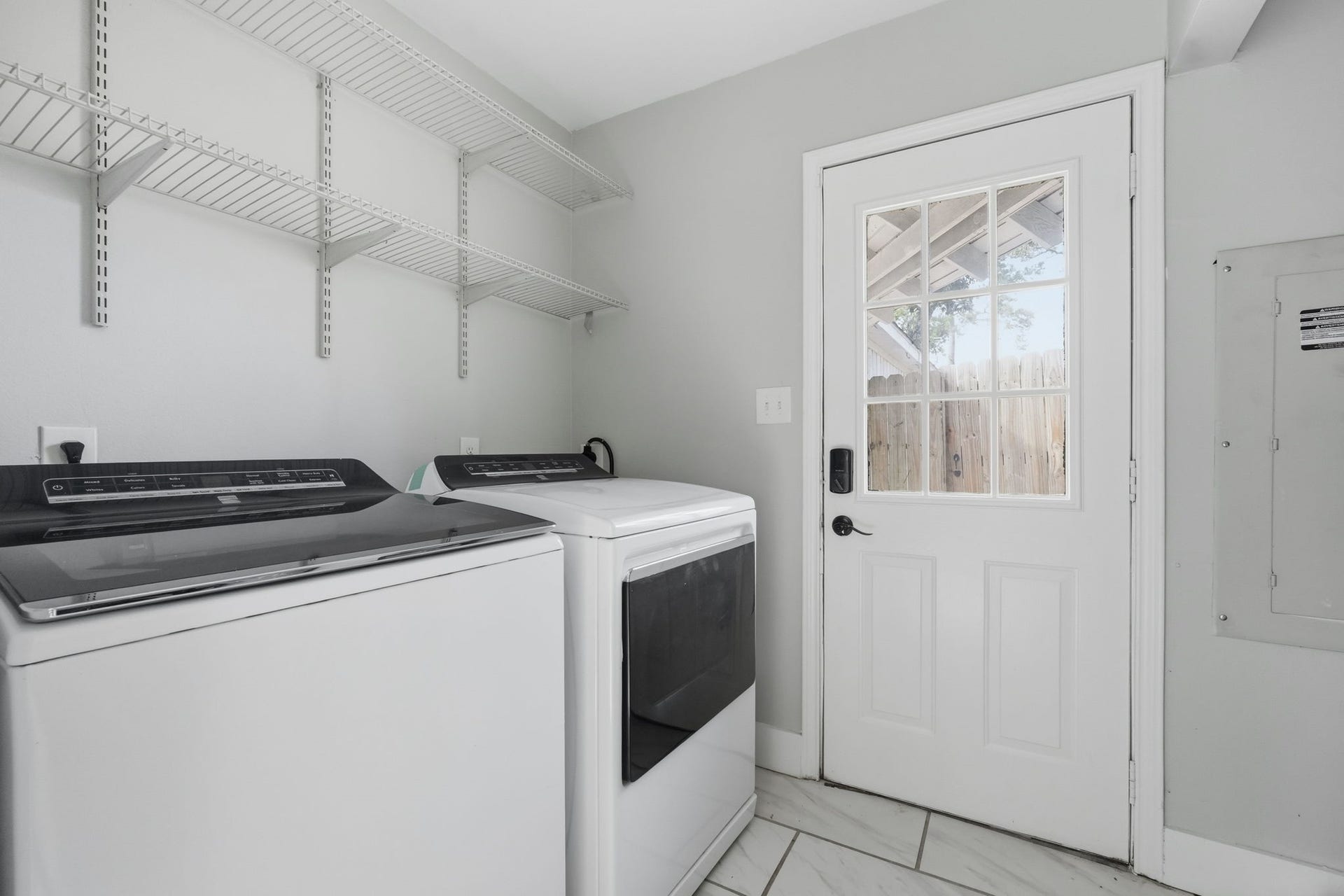 This functional laundry room features modern appliances, shelving, and convenient outdoor access.