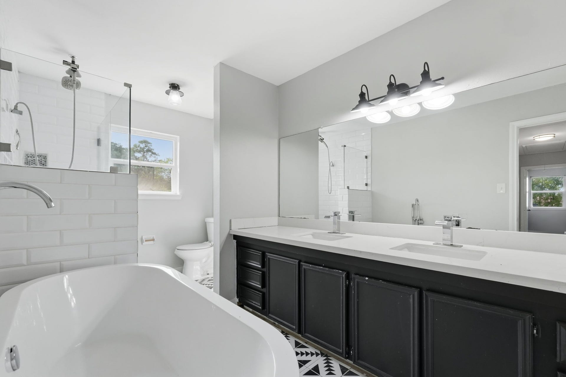 This elegant bathroom has a large soaking bathtub and a lovely adjacent rainfall shower.