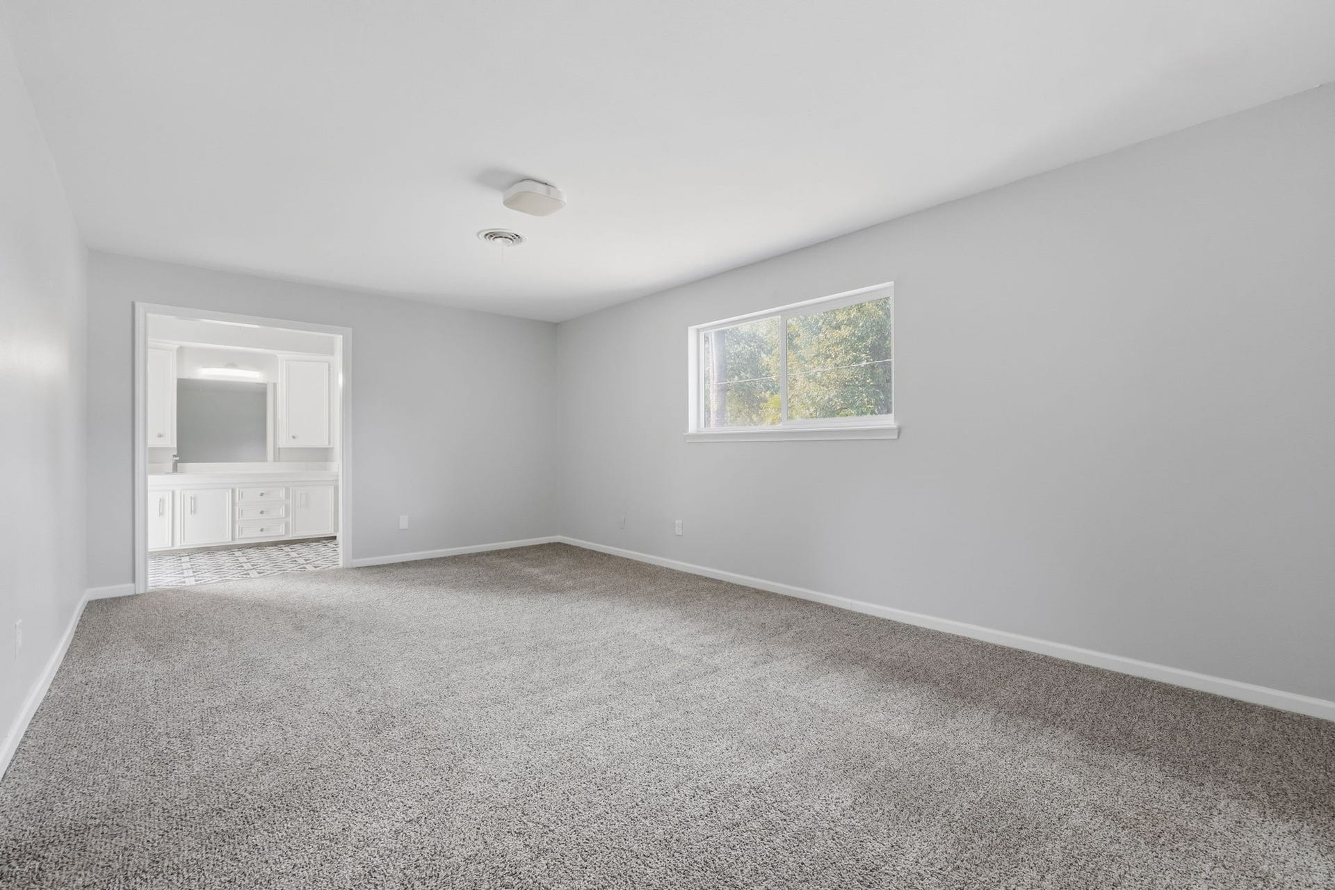 This bedroom has a large window for natural light, and an ensuite bathroom for convenience.