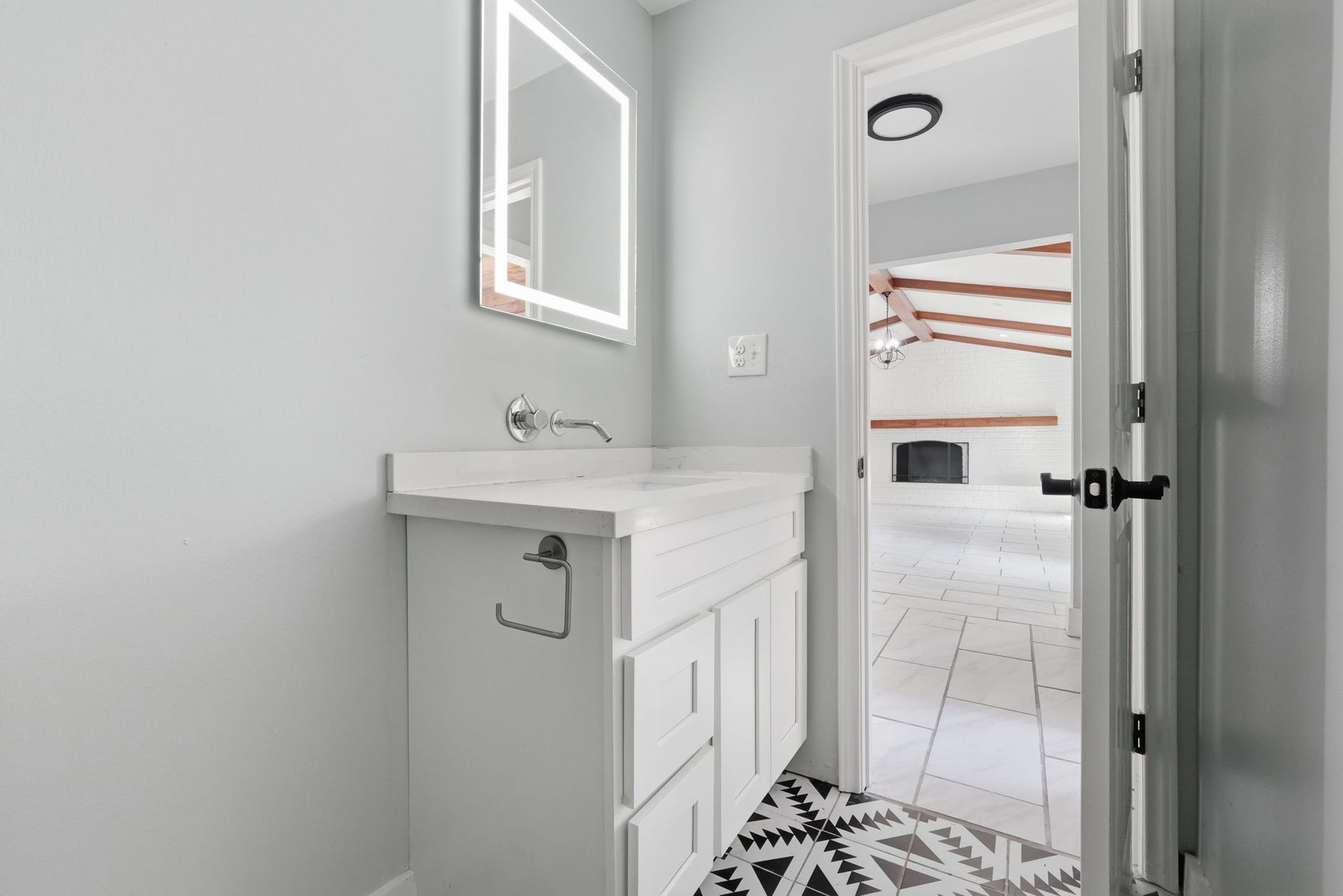 This half bath with an illuminated mirror leads into the spacious living area.