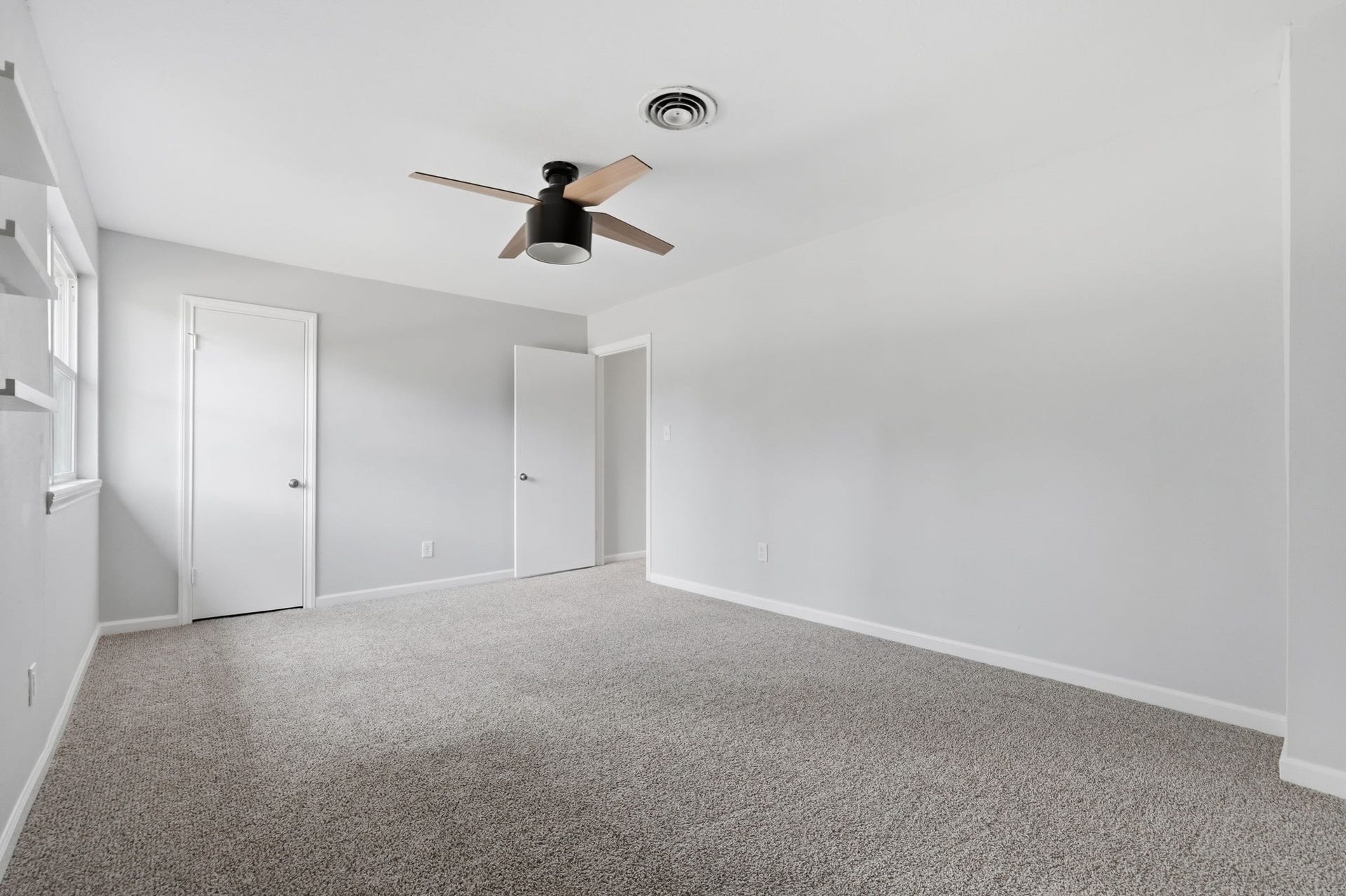 This large bedroom features a modern ceiling fan and bright natural light.