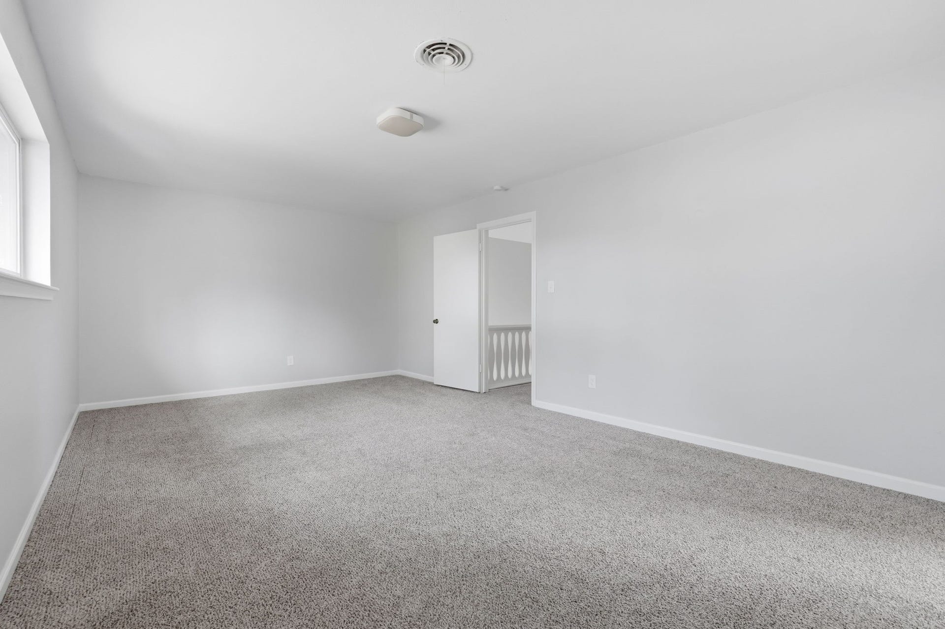 Spacious and bright room with neutral carpeting.
