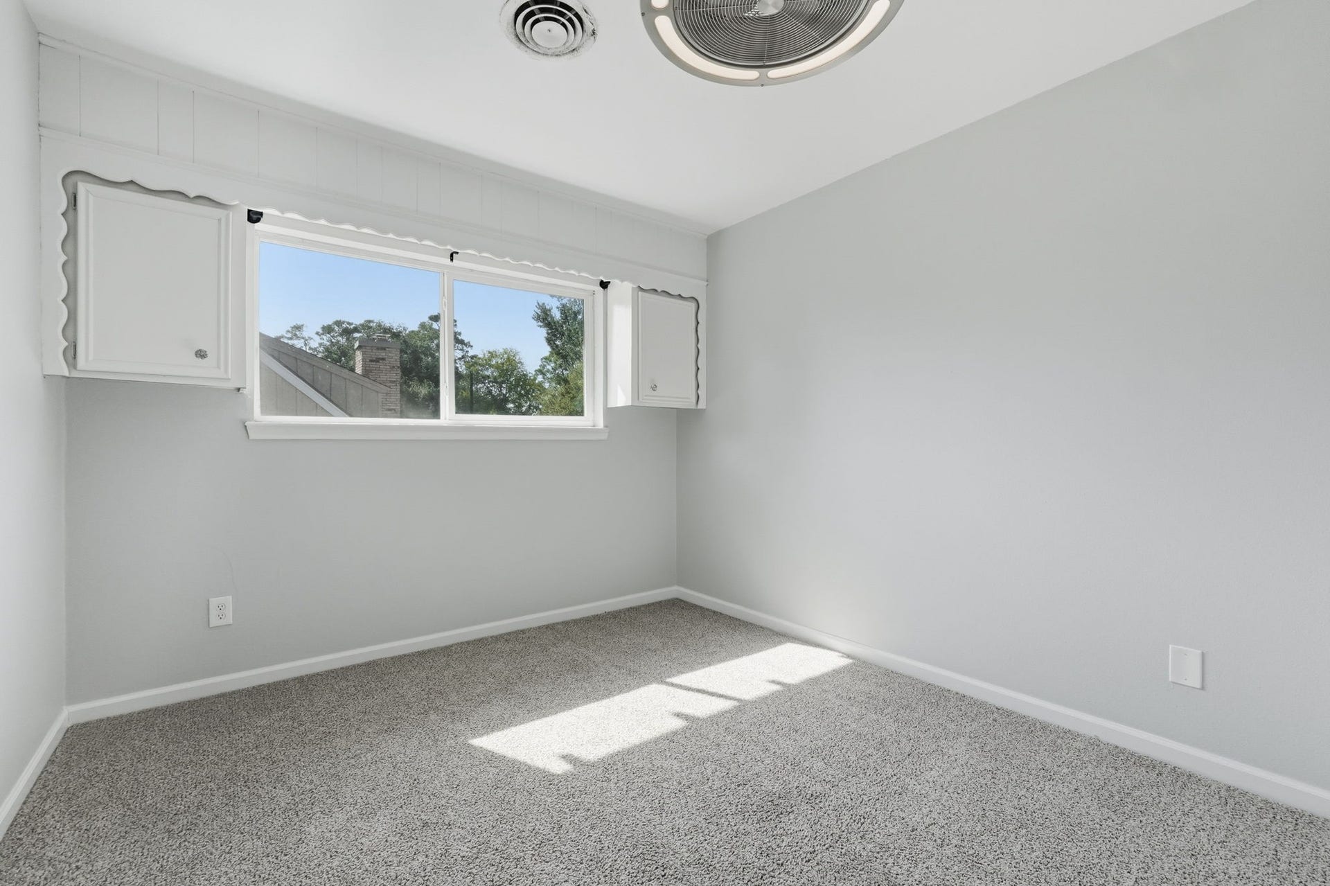 This extra room, is bright room features a large window and gorgeous cabinetry and shelving, perfect for a home office.