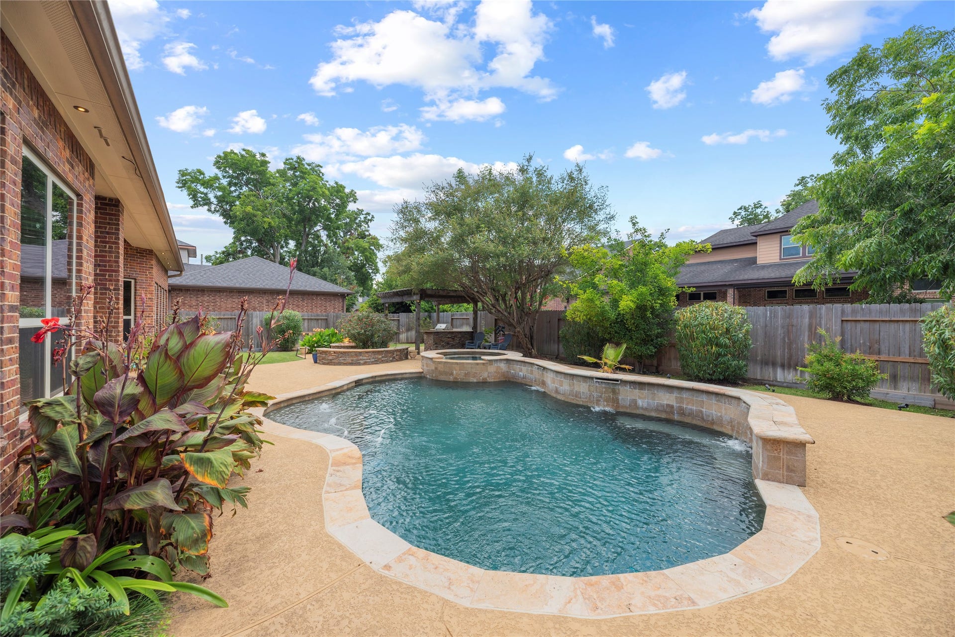 6115 Duke Trail Lane, Sugar Land, TX 77479 Sparkling pool and spa with water fall features - surrounded by lush landscaping.