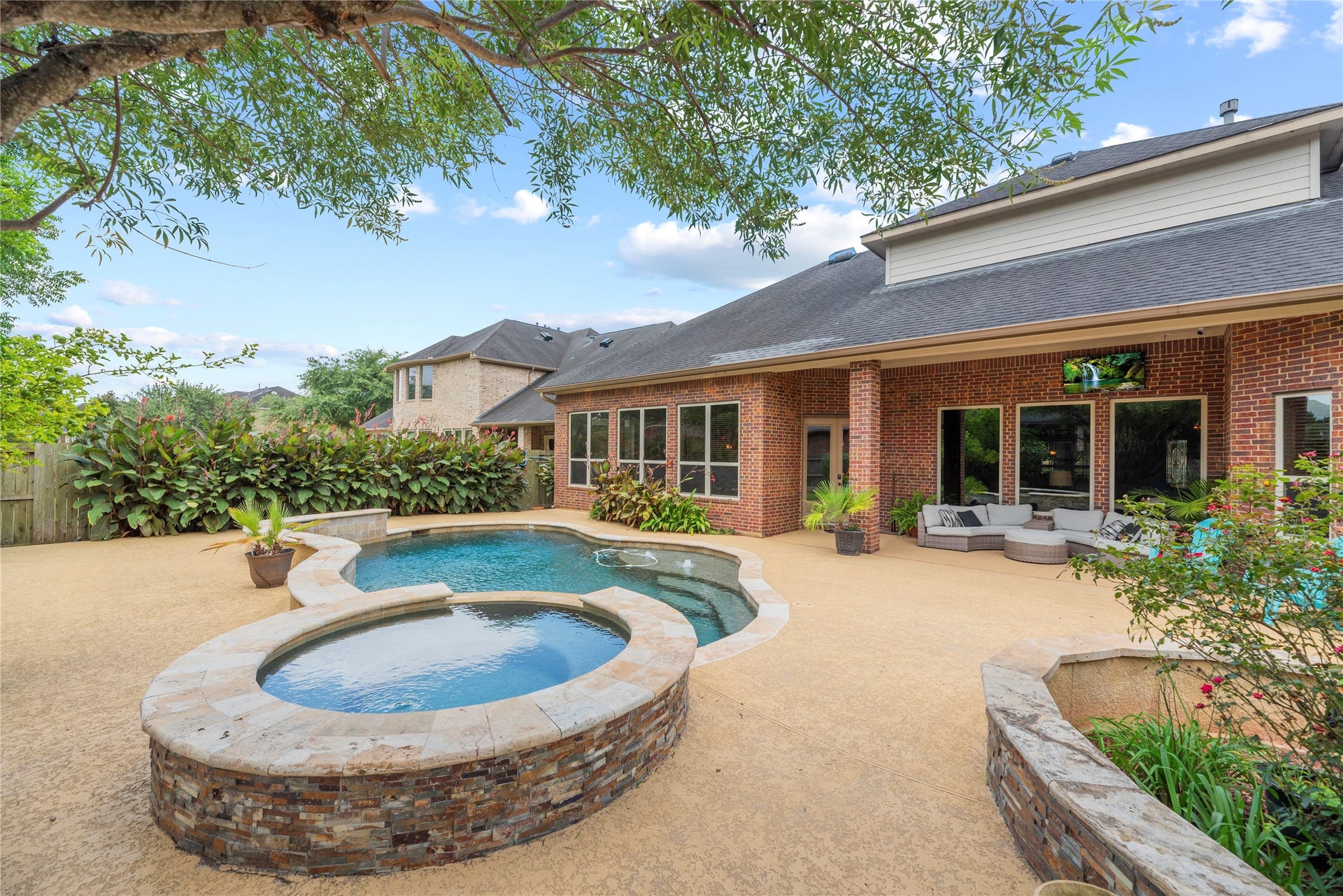 6115 Duke Trail Lane, Sugar Land, TX 77479 Sparkling pool and spa with water fall features - surrounded by lush landscaping.