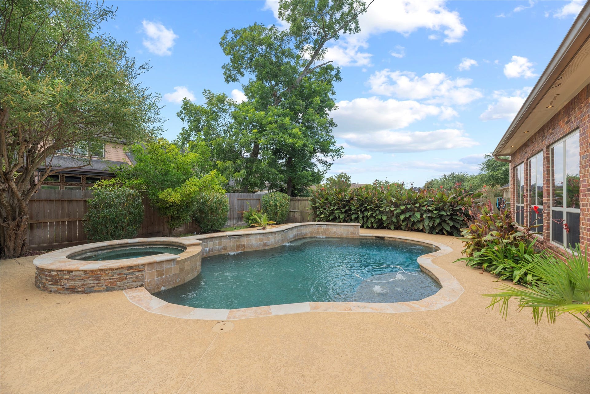 6115 Duke Trail Lane, Sugar Land, TX 77479 Sparkling pool and spa with water fall features - surrounded by lush landscaping.