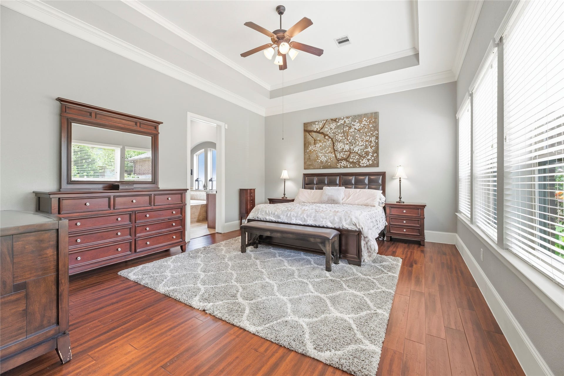 6115 Duke Trail Lane, Sugar Land, TX 77479 Spacious primary suite with wood floors, coffered ceilings, sleek paint, and large windows overlooking your private backyard oasis.