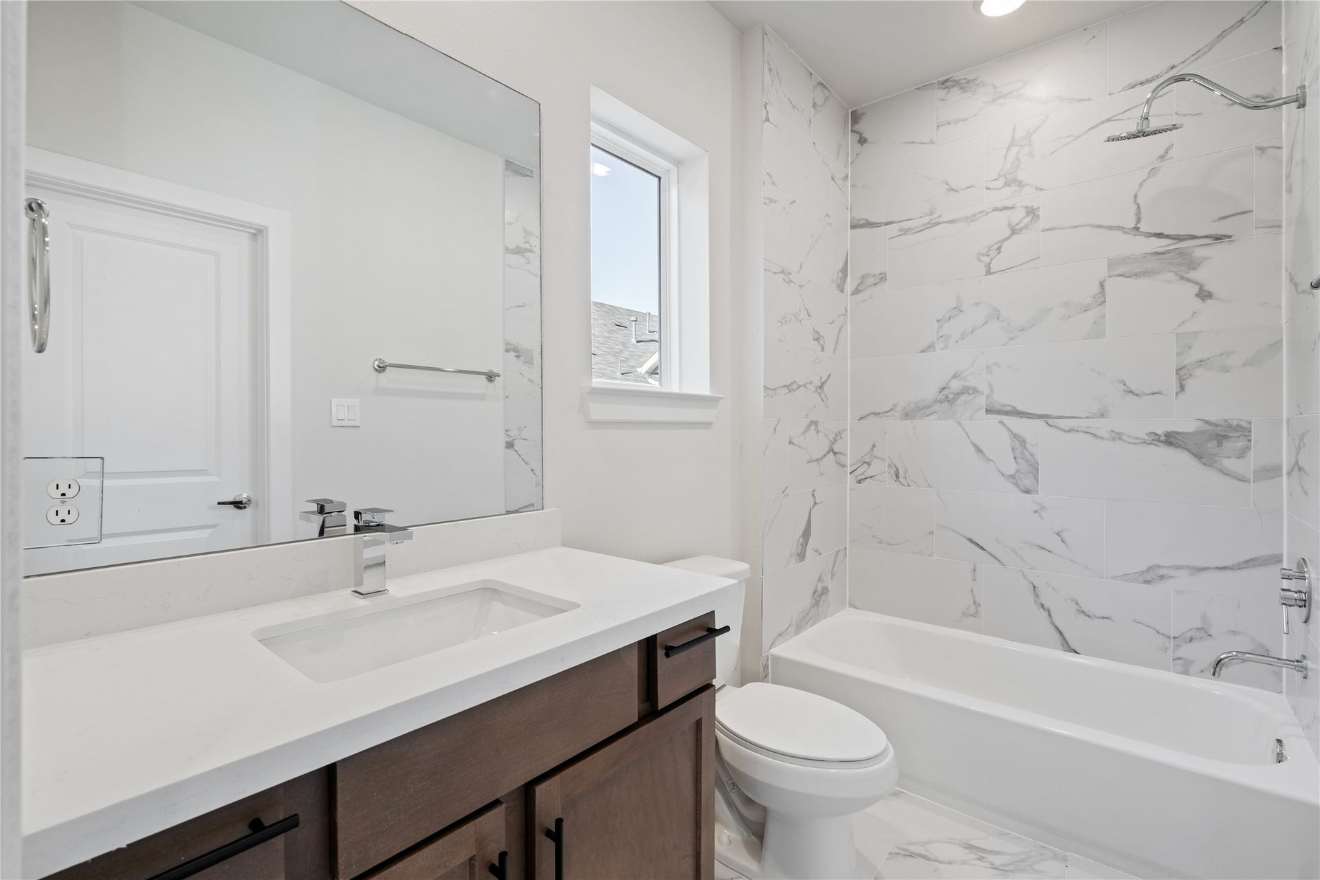 6441 Rena Street, Houston, TX 77092 Secondary bath with a full tub-shower wrapped in large format marble-look tile a finish you don't usually see at this level.