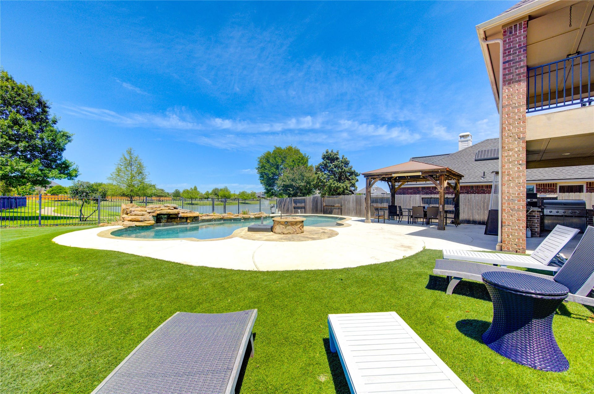 Resort-style backyard featuring a saltwater lagoon pool with rock waterfall and lush landscaping