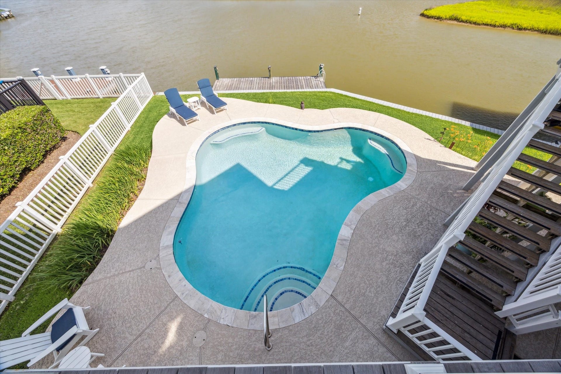 1 Shell Key, Hitchcock, TX 77563 This aerial view showcases a beautifully designed, swimming pool set along a waterfront backdrop. The pool is surrounded by a spacious deck with ample room for lounging