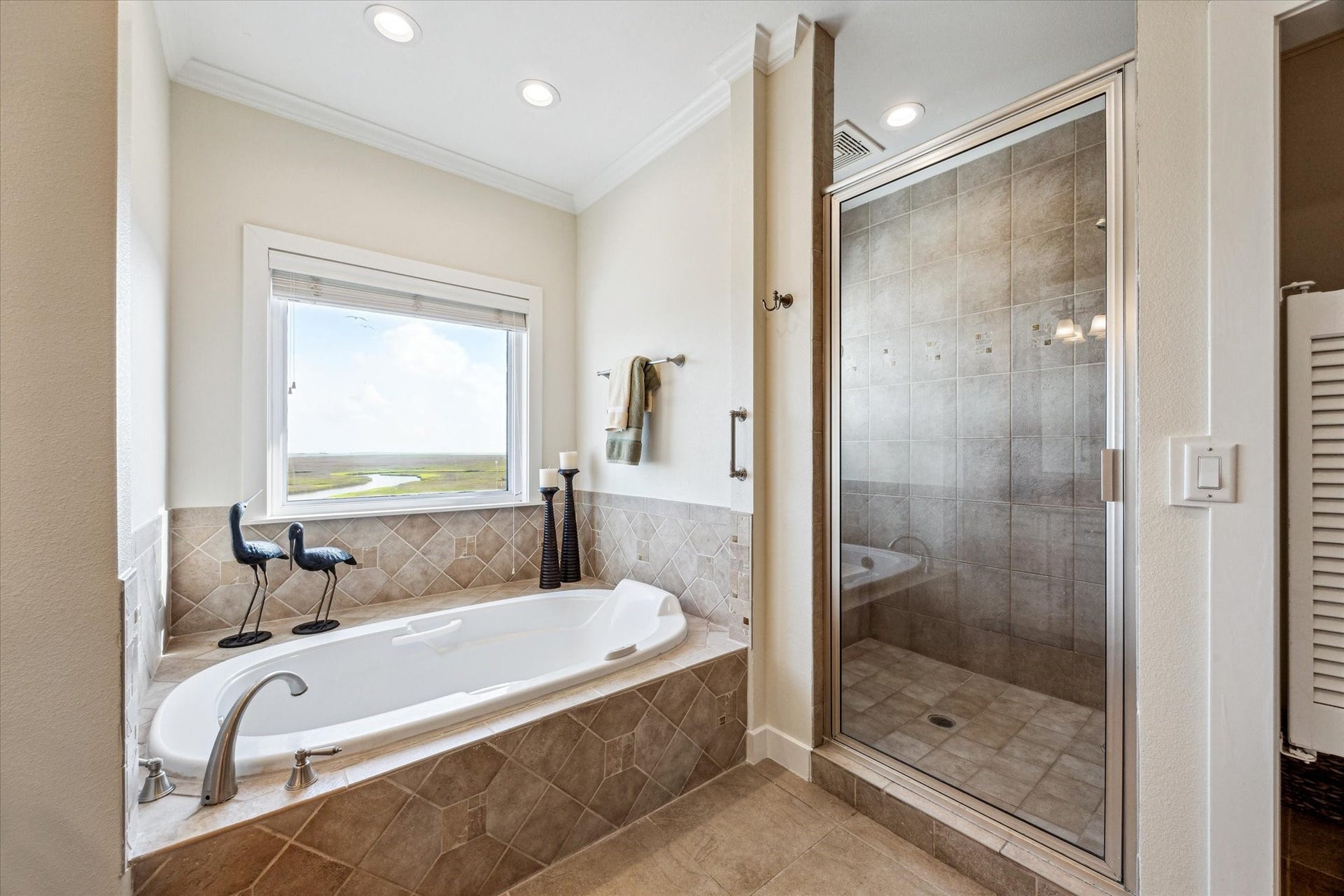 1 Shell Key, Hitchcock, TX 77563 The primary bathroom features a luxurious Bain garden tub with an air bubbler for a spa-like experience, while the spacious shower offers stunning views of the surrounding waters and coastal wetlands. A separate glass-enclosed shower adds function and style, creating a relaxing and beautifully finished retreat