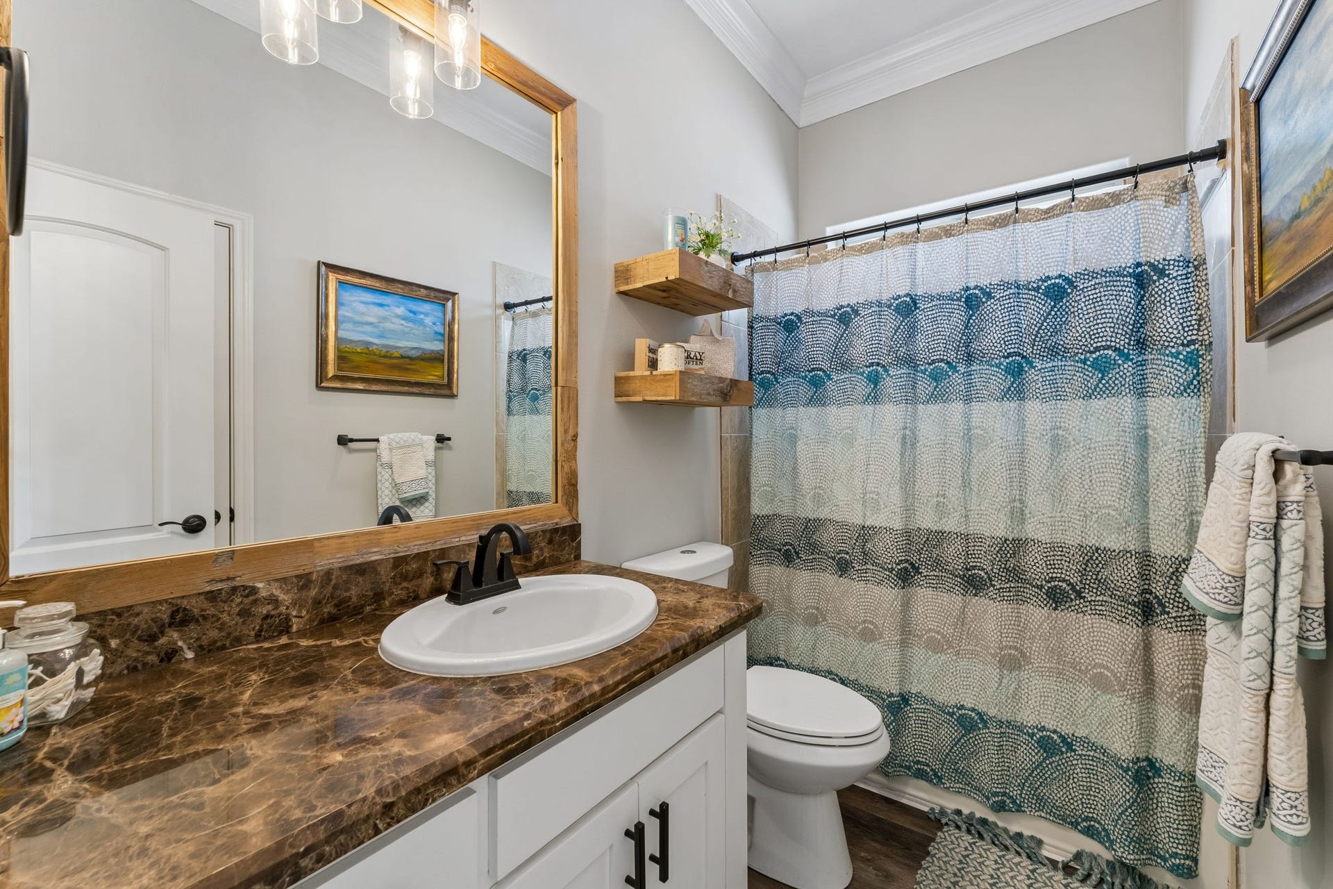 1623 Dick Bay Drive, San Leon, TX 77539 Full bath features a spacious vanity with rich stone countertops and a large framed mirror. Floating wood shelves add warmth and convenient storage.