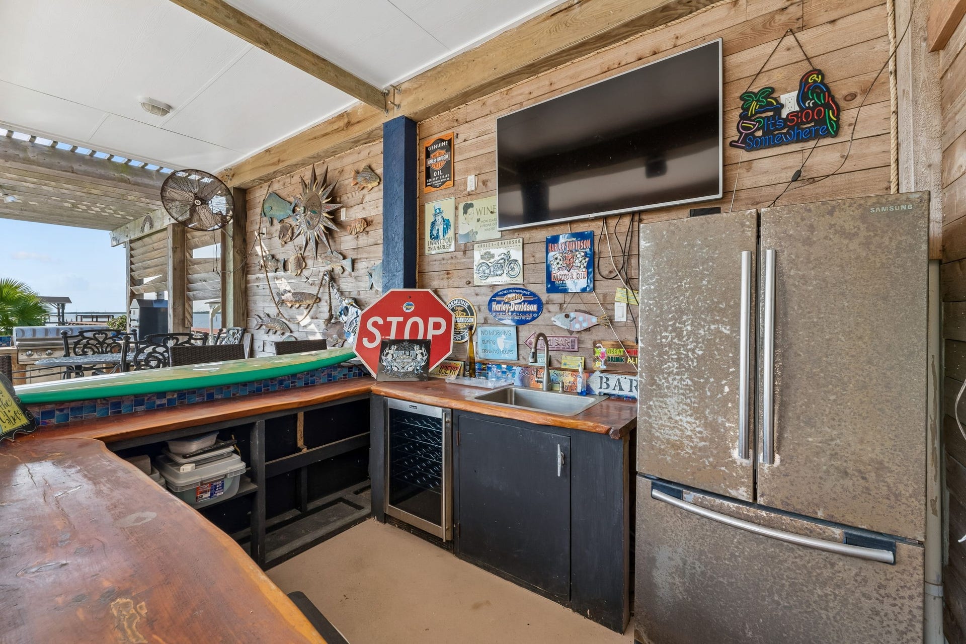 1623 Dick Bay Drive, San Leon, TX 77539 Fully equipped outdoor bar features a sink, full size refrigerator, mounted TV, and generous counter space. Rustic wood finishes add character to this inviting entertainment zone.