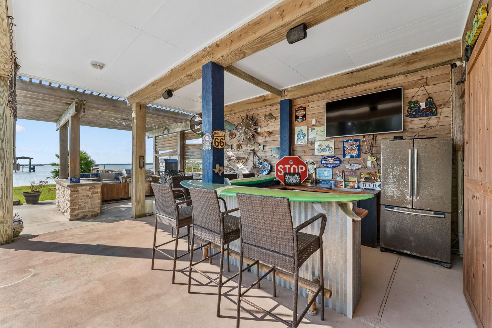1623 Dick Bay Drive, San Leon, TX 77539 Covered outdoor bar creates a fun gathering spot with generous seating, a refrigerator, and mounted TV. Just steps from the bay, it is perfectly positioned for effortless waterfront entertaining.