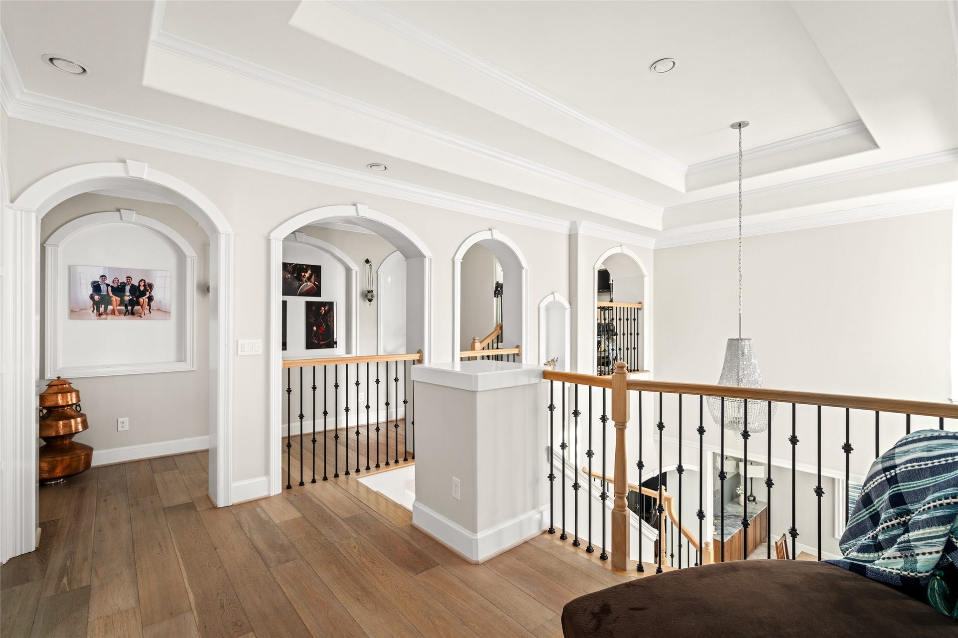 Wide plank white oak landing upstairs, art niches, unique architectural trimwork, built-in bookshelves, tray ceilings, recessed lighting, room for a small reading nook atop the staircase.