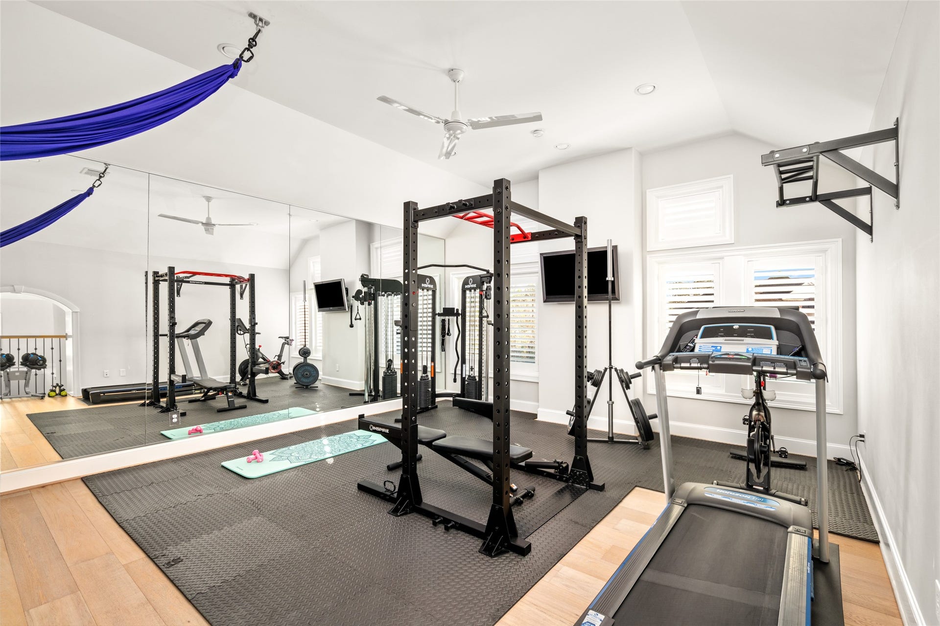 The bonus room is located on the second level, currently used as a gym.  This room is amazing!  Modern ceiling fan, mirrored wall, TV included, wide-plank, white oak flooring (under the gym mats), plantation shutters, walk-in closet (used as Tech Room) by current sellers.   The purple ribbon on the top of the photo is aerial silks installation.