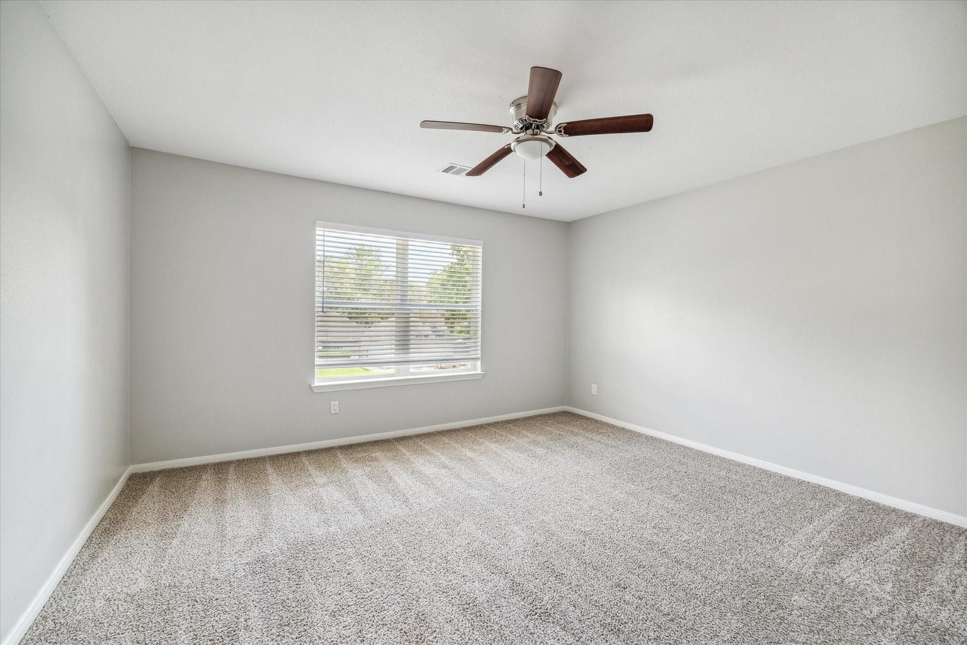 6003 Ancient Oaks Drive, Humble, TX 77346 Bright secondary bedroom with neutral flooring, freshly painted walls, a ceiling fan, and a large window overlooking the outdoors.