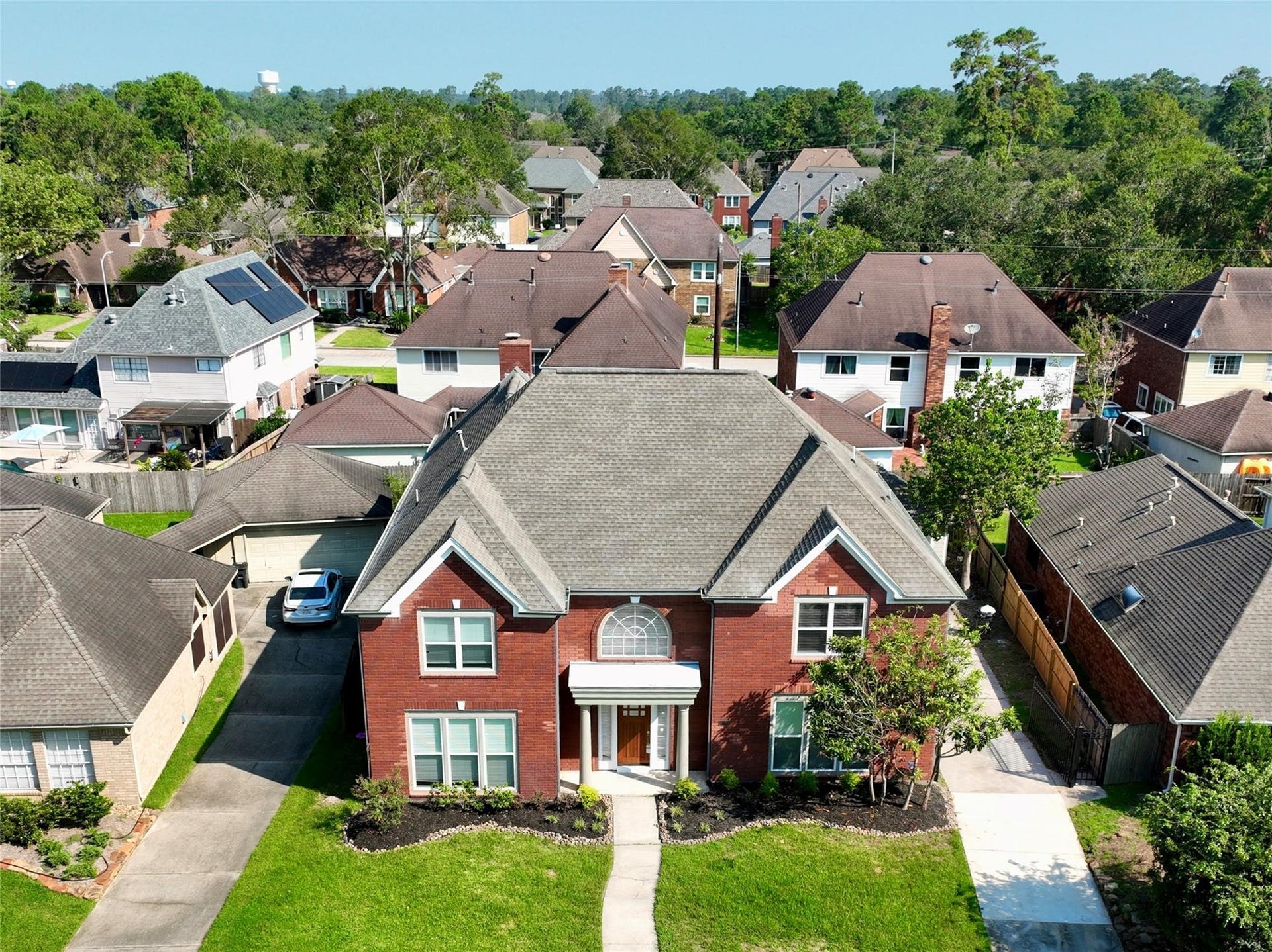 6003 Ancient Oaks Drive, Humble, TX 77346 Front-facing aerial view highlighting the homes two-story brick faade, expansive lawn, and placement within the established community.