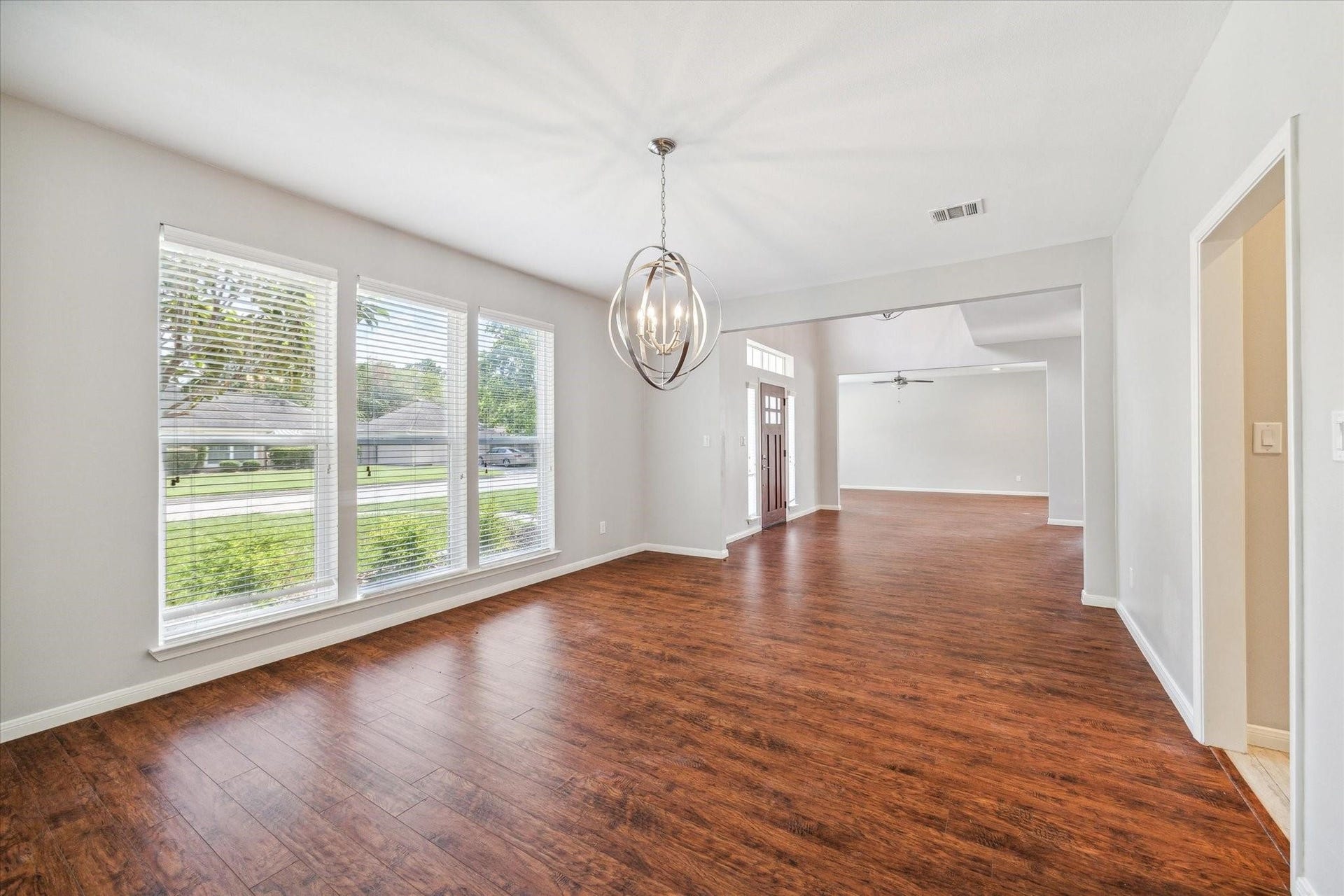 6003 Ancient Oaks Drive, Humble, TX 77346 Bright and spacious living area with multiple windows, warm wood-look flooring, recessed lighting, and plenty of room for comfortable seating.