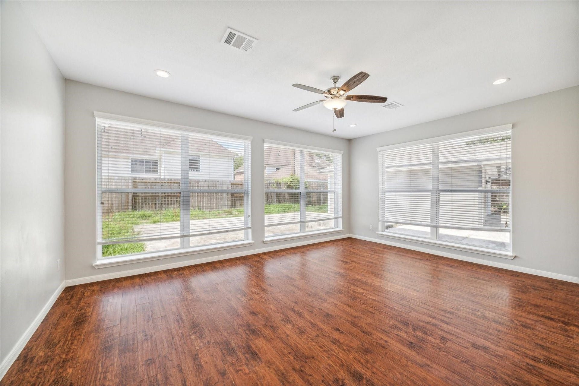 6003 Ancient Oaks Drive, Humble, TX 77346 Light-filled living room with large windows overlooking the yard, a ceiling fan, and ample space for multiple seating arrangements.