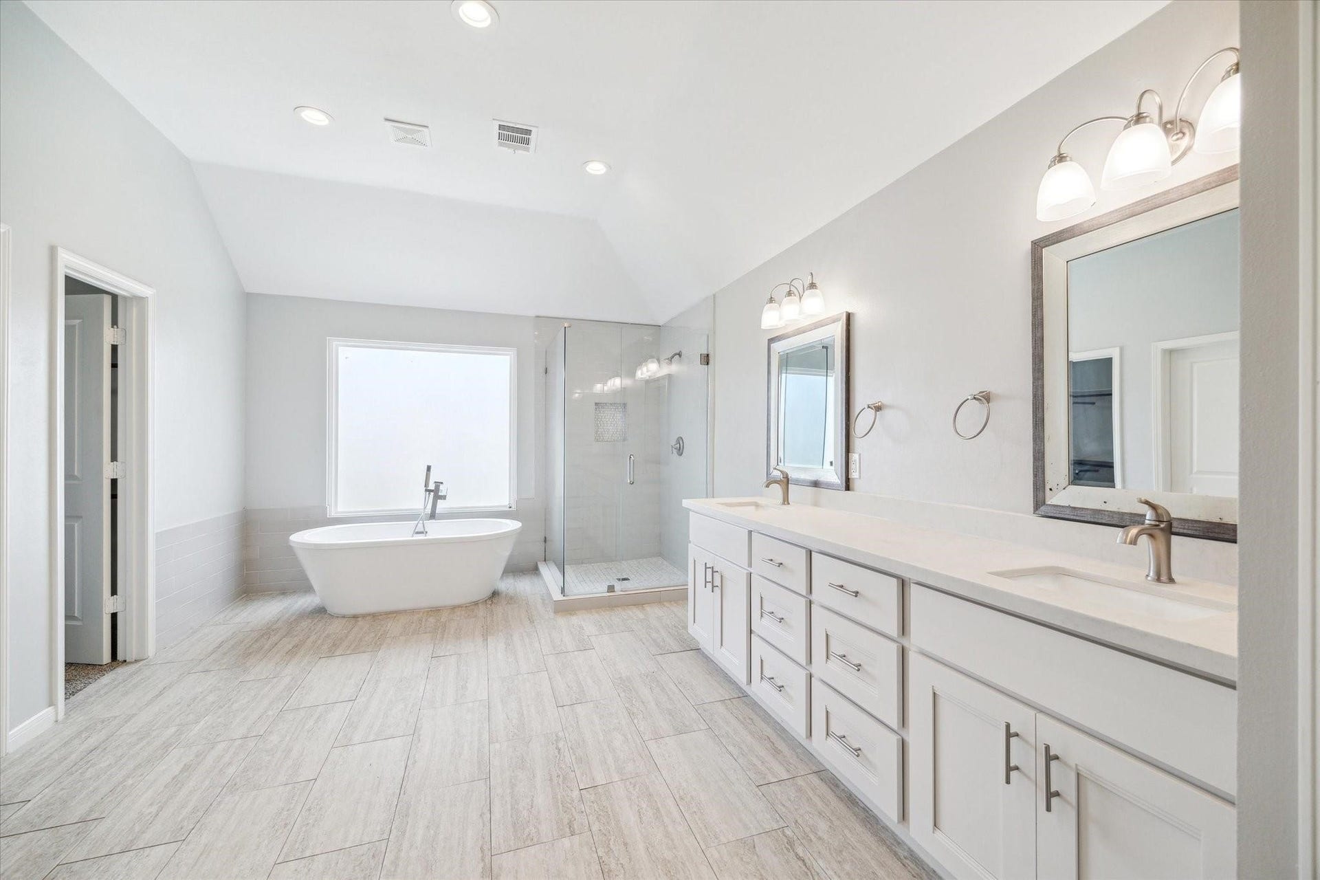 6003 Ancient Oaks Drive, Humble, TX 77346 Spacious primary bathroom with a long double-sink vanity, abundant cabinet storage, large mirrors, and a separate soaking tub.