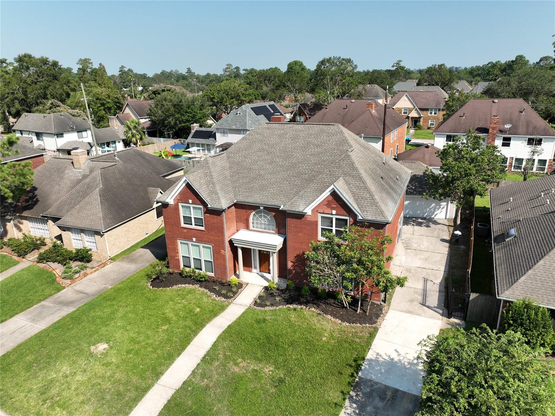 6003 Ancient Oaks Drive, Humble, TX 77346 Elevated aerial view showcasing the homes brick exterior, spacious front lawn, neighboring homes, and established residential setting.