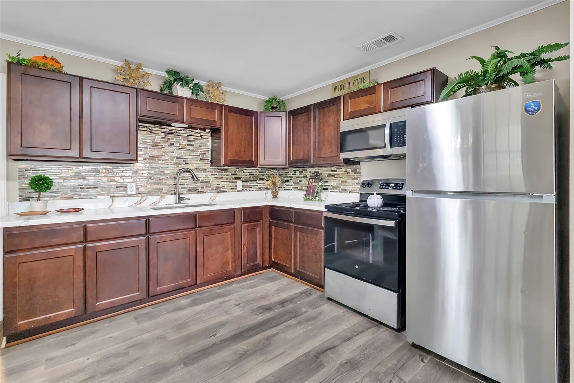 604 19th Avenue N, Texas City, TX 77590 Attractive kitchen featuring abundant cabinet storage, stainless-steel appliances, updated flooring, and decorative tile backsplash.