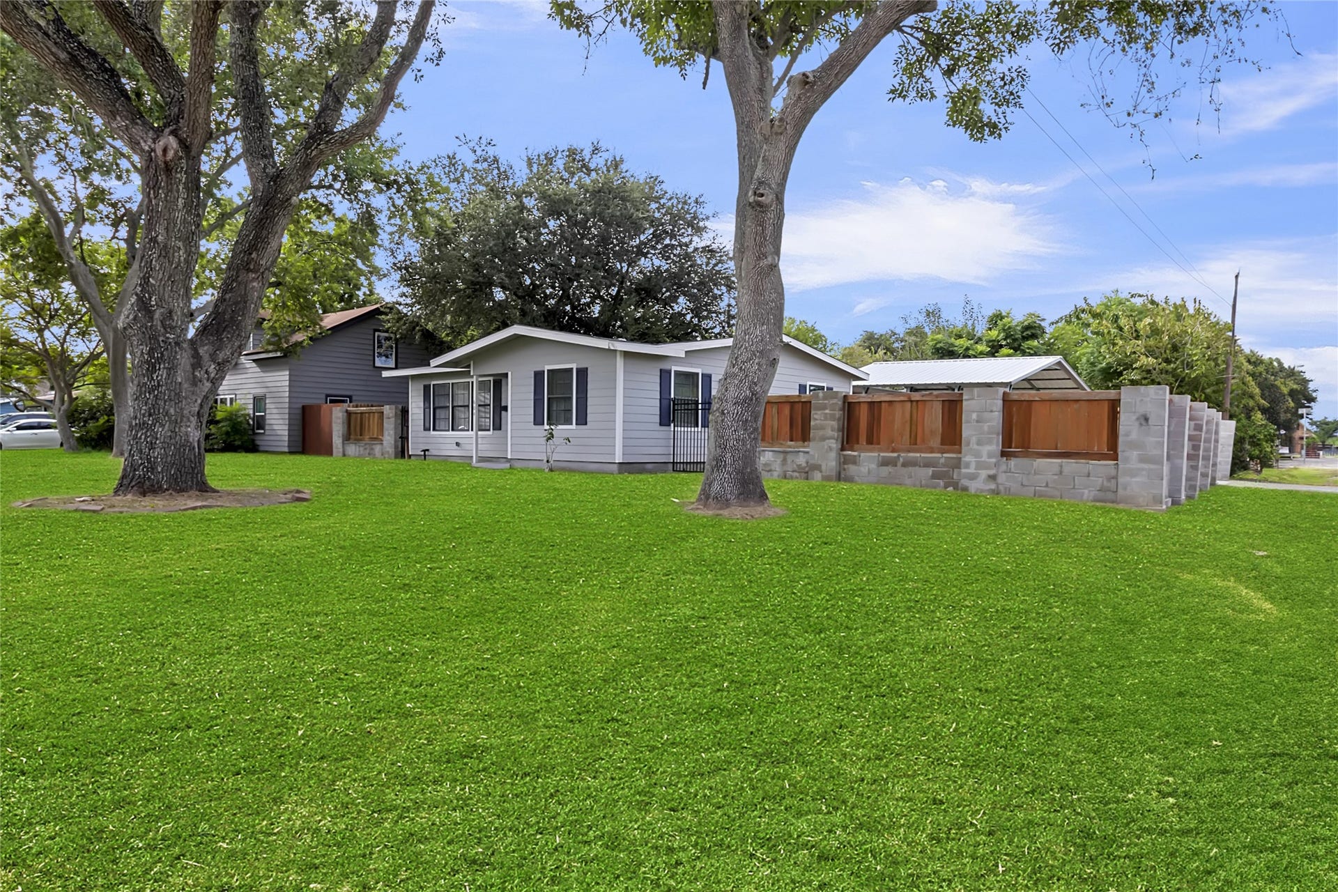 604 19th Avenue N, Texas City, TX 77590 Wide exterior view showcases the large corner lot, mature shade trees, expansive lawn, and newly installed privacy fencing.